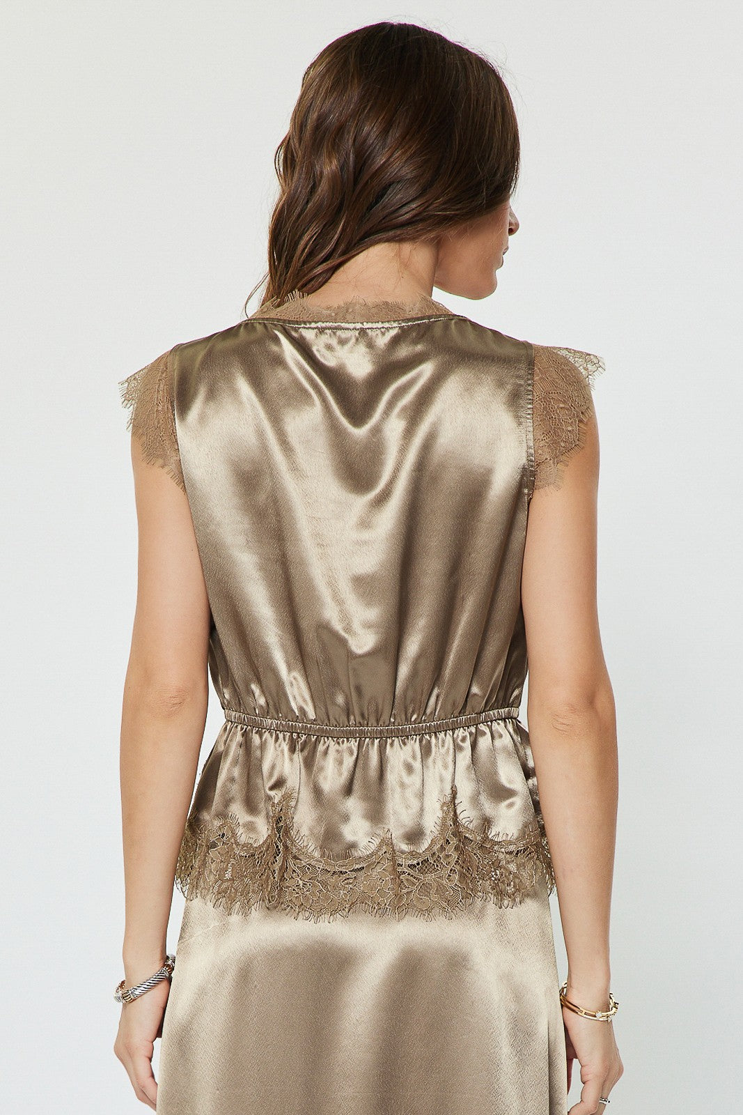 A feminine metallic satin blouse featuring lace-trimmed details, delicate cap sleeves, an elasticized waist, and a flattering peplum hem.