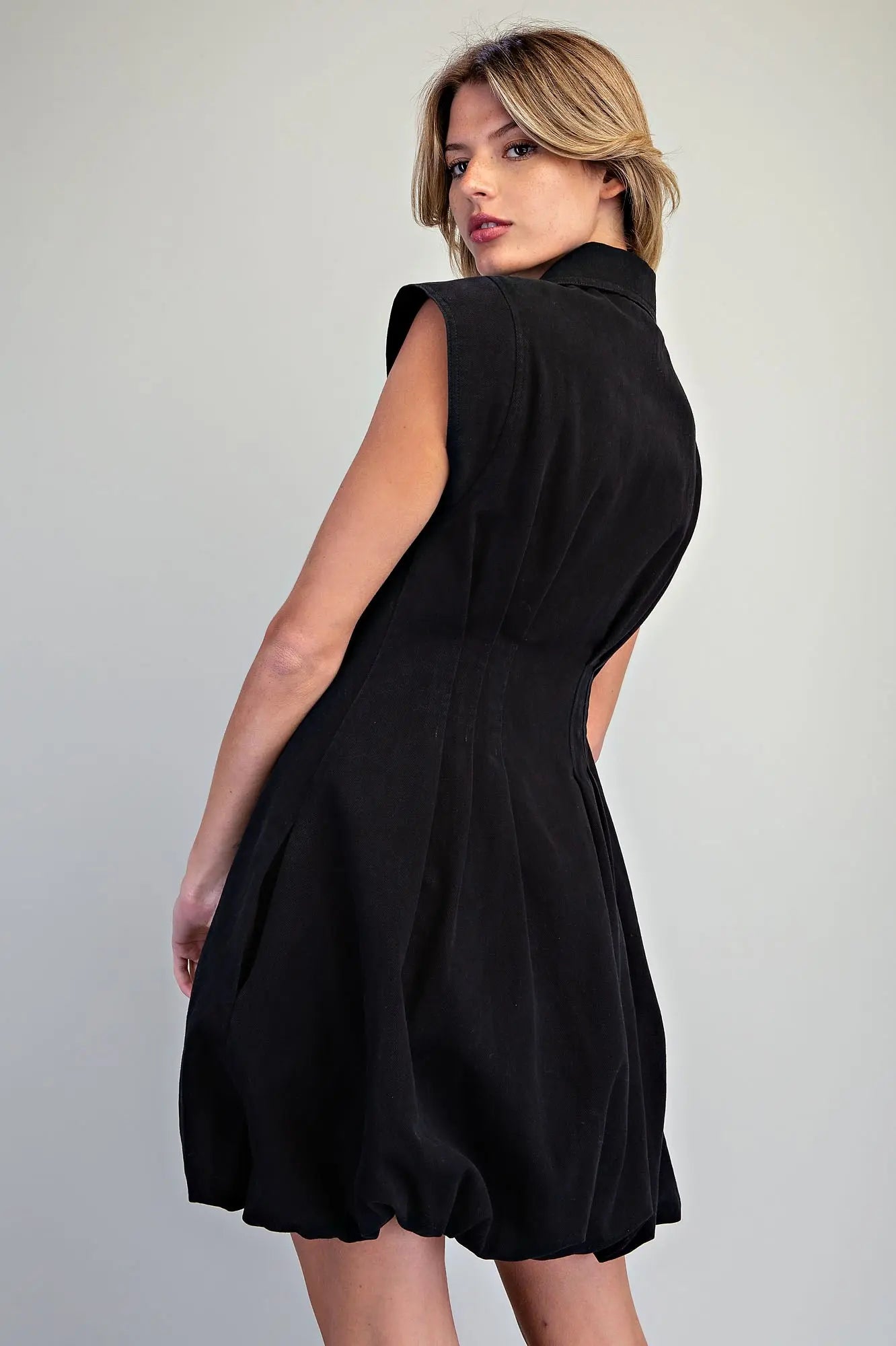 A chic pleated mini dress featuring a structured sleeveless silhouette, sharp collar, exposed zip front, and playful bubble hem for a polished statement look.
