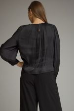 A polished long sleeve top featuring elegant keyhole details, gathered texture, and refined gold hardware at the neckline.

