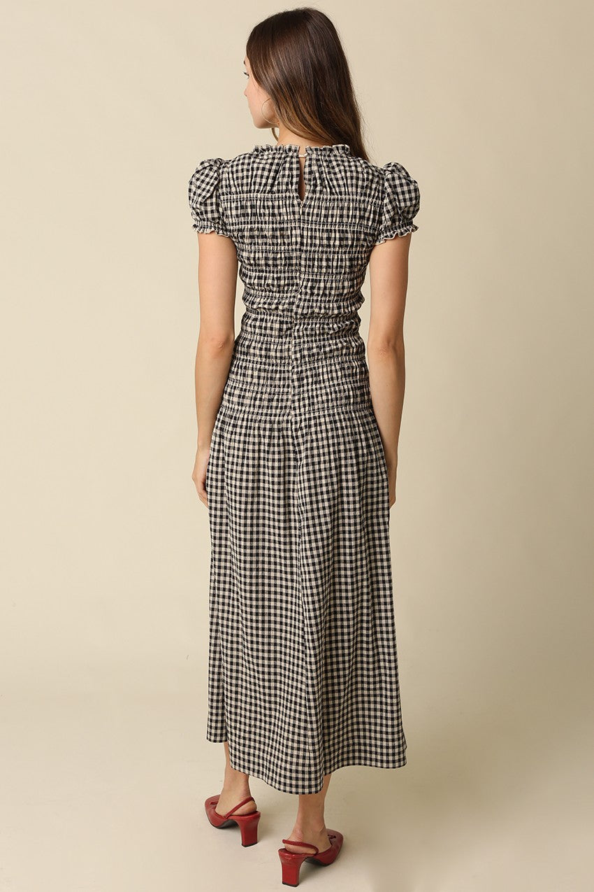 A romantic plaid maxi dress featuring soft puff sleeves, a fitted smocked bodice, and a flowing gathered skirt for an effortlessly feminine silhouette.