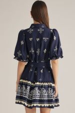 A charming printed mini dress featuring puff sleeves, a classic shirt collar, self-tie waist, and playful ruffle hem finished with a contrasting border print.