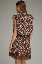 A statement-making zebra print mini dress featuring a mock neckline, self-tie shoulder details, elastic waist, and delicate lace-trimmed hem.

