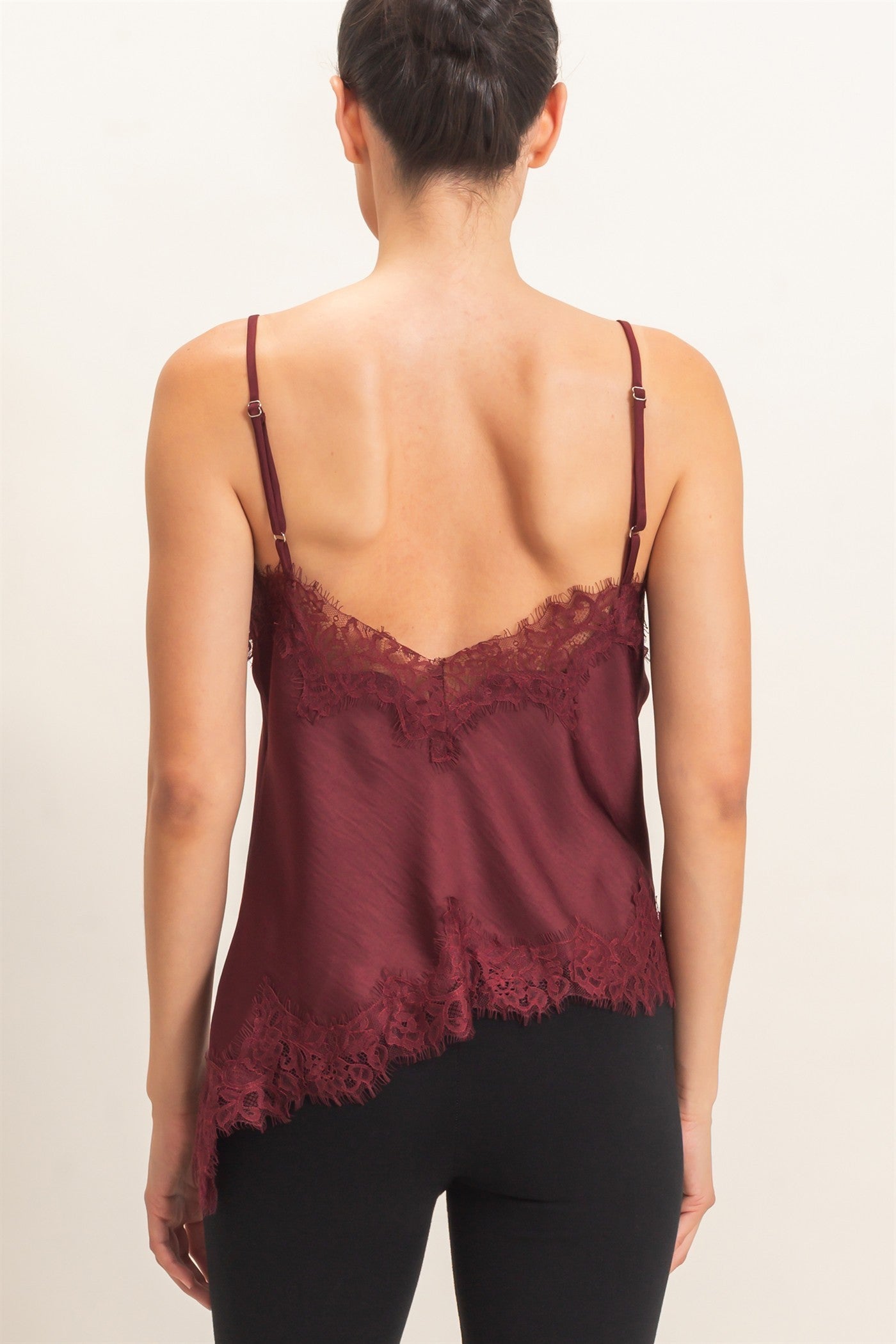 A delicate asymmetrical lace camisole with adjustable straps and feminine lace trim, designed to elevate your favorite layered looks.