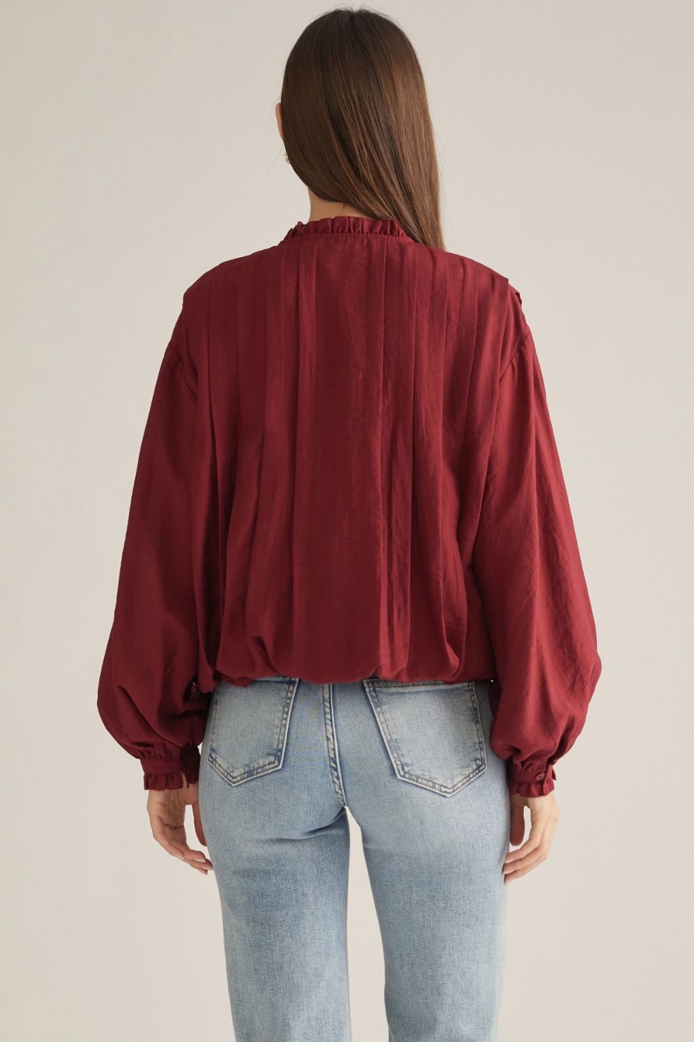 A romantic long-sleeve blouse featuring a ruffled high neckline, delicate front ruffle trim, and elegant button details for a timeless feminine look.

