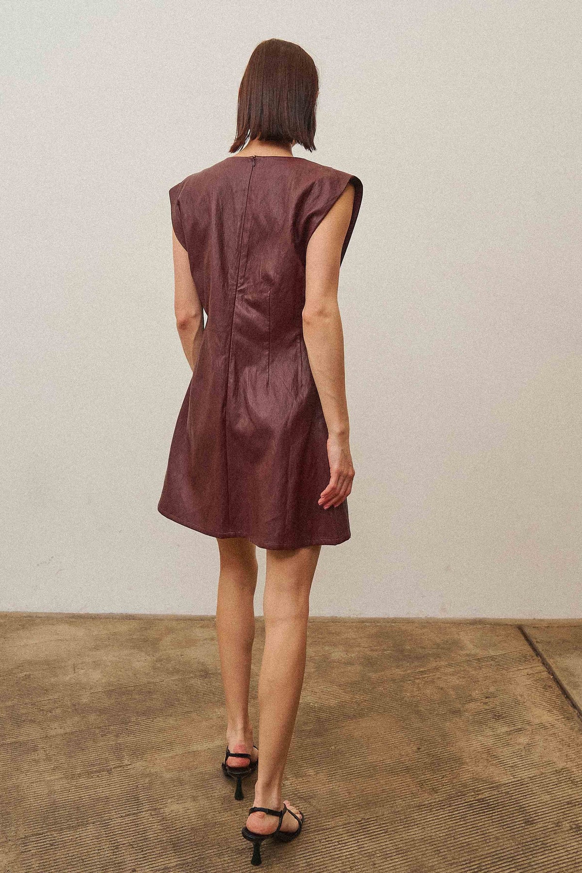 A sleek vegan leather mini dress featuring a subtle shimmering finish for a chic, statement-making look.
