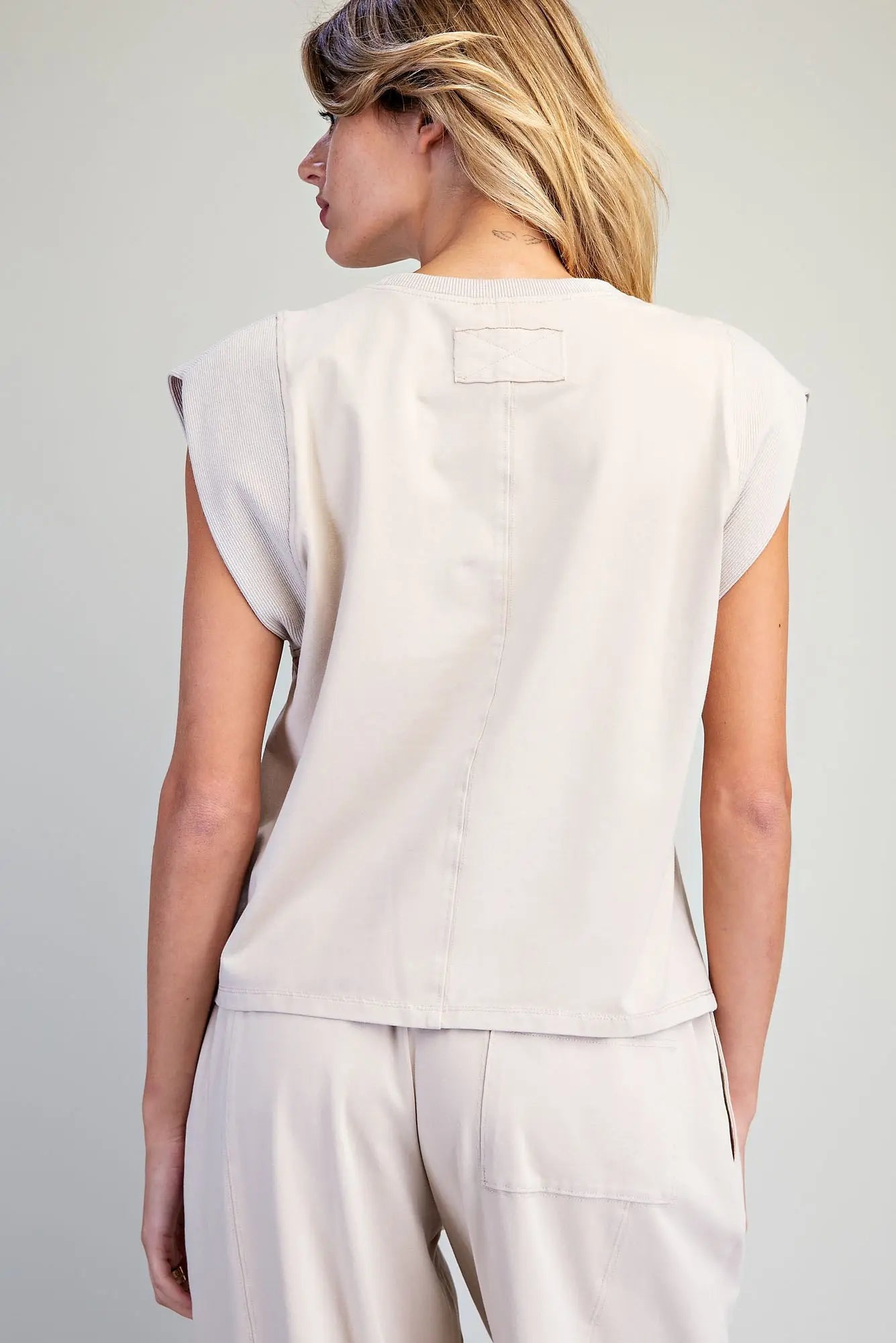 A relaxed washed top featuring structured cap shoulders, ribbed trim detailing, and a minimalist silhouette for effortless everyday style.