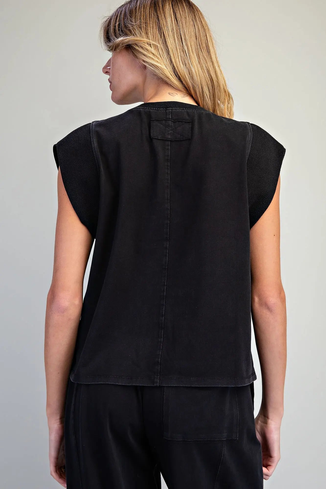 A relaxed washed top featuring structured cap shoulders, ribbed trim detailing, and a minimalist silhouette for effortless everyday style.