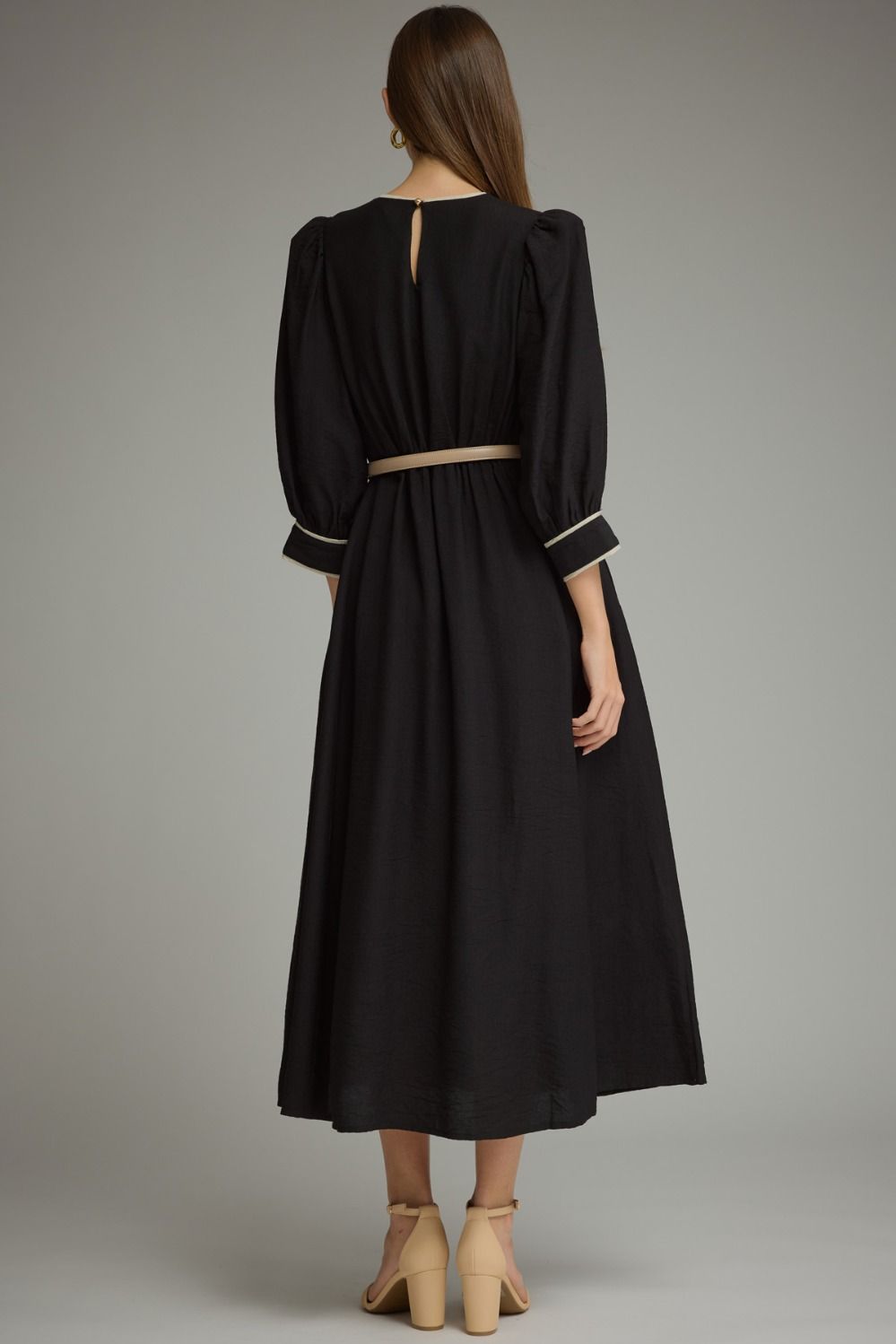 A polished ¾-sleeve midi dress featuring feminine puff sleeves, contrast piping, a defined elastic waist, and a removable buckle belt.