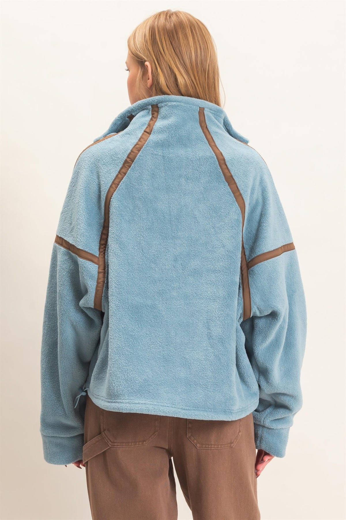 A cozy fleece half zip pullover featuring a high funnel neck, sporty contrast trim, oversized curved pockets, and an adjustable drawstring hem.