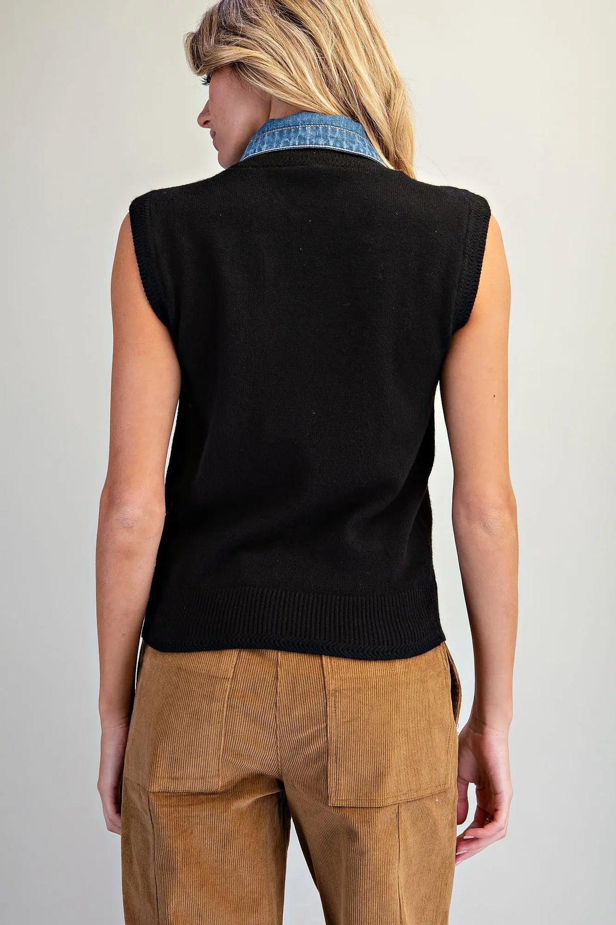 A stylish sleeveless knit top featuring a V-neckline, oversized denim tie-neck bow, and textured ribbed trim for a unique, polished look.
