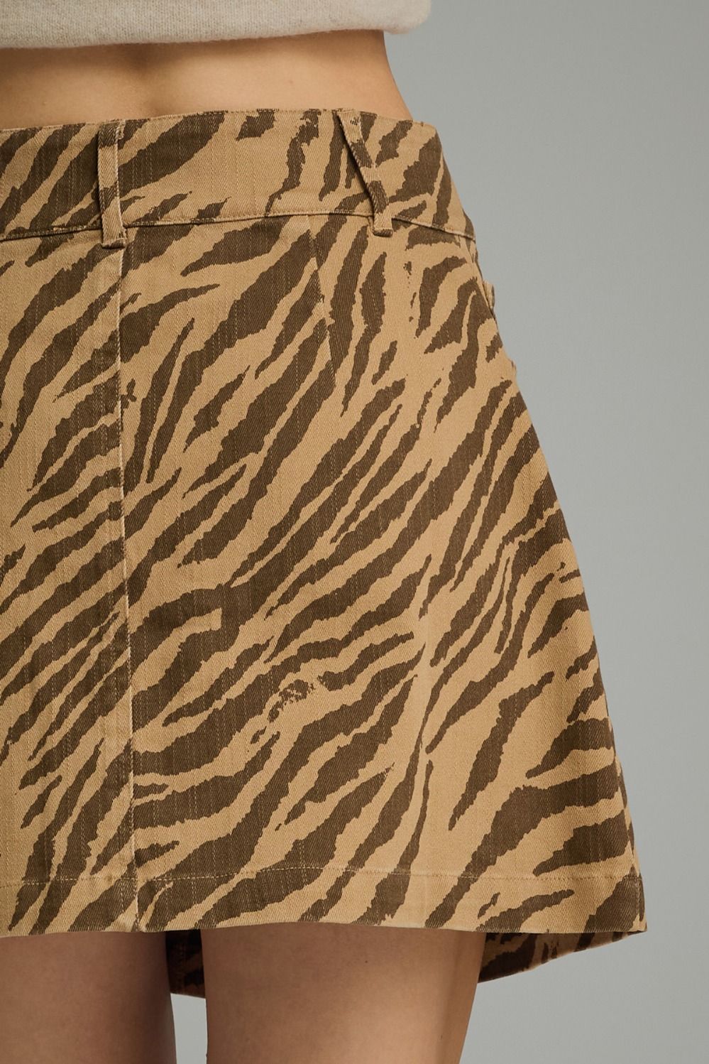 A bold zebra print mini skirt featuring a button-front design, front pocket details, and a flattering everyday silhouette.
