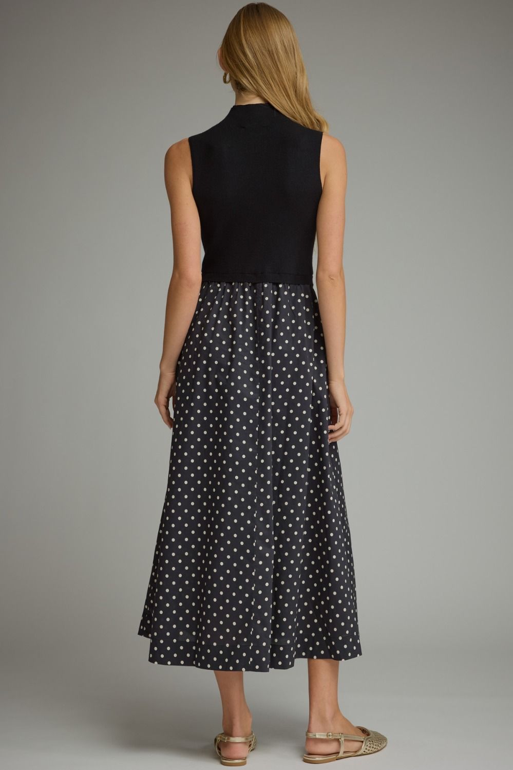 A sophisticated polka dot midi dress featuring a sleek solid knit bodice, mock neckline, and feminine flowing silhouette.


