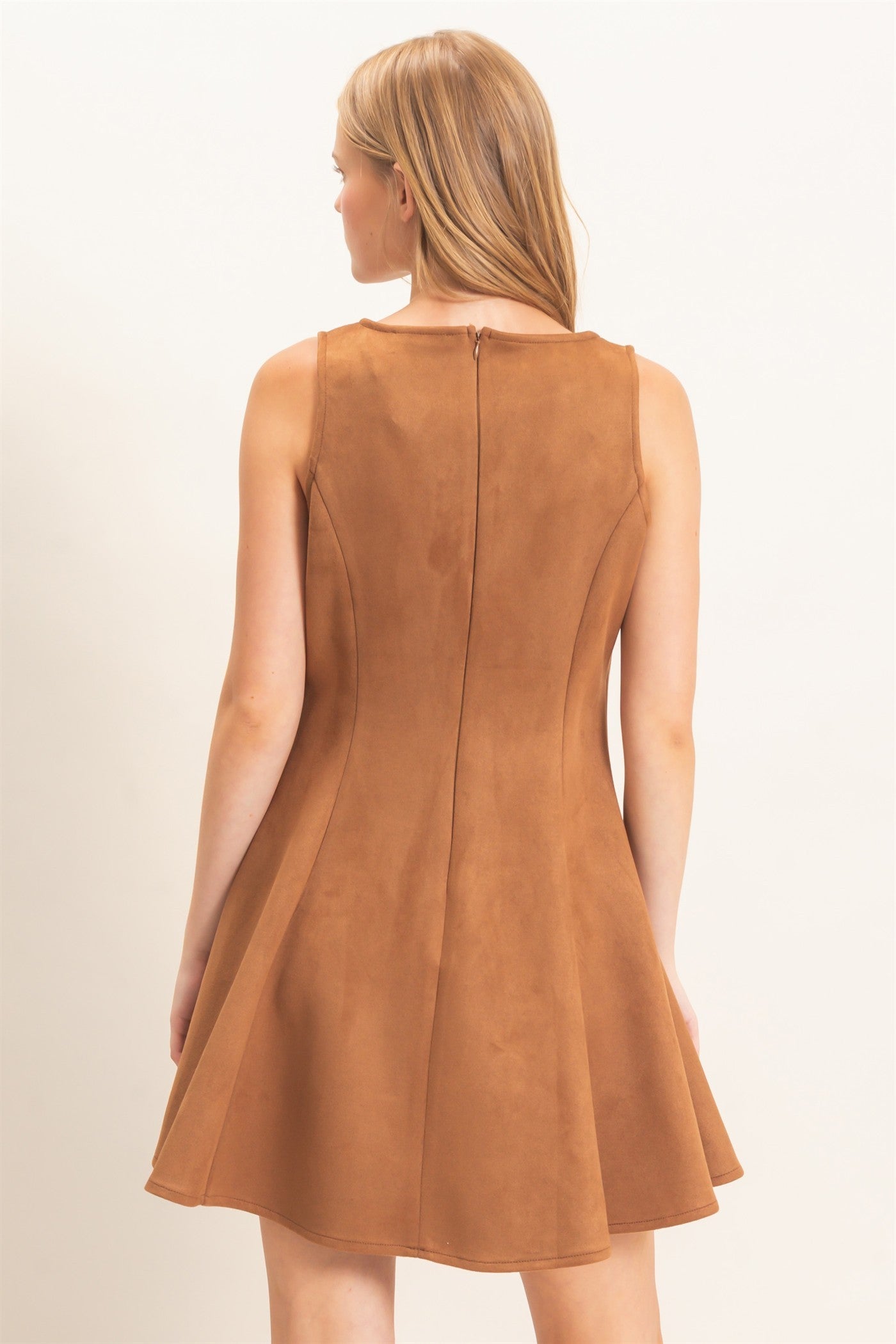 A sophisticated sleeveless suede mini dress with a classic round neckline and flattering flared silhouette that effortlessly transitions from day to night.
