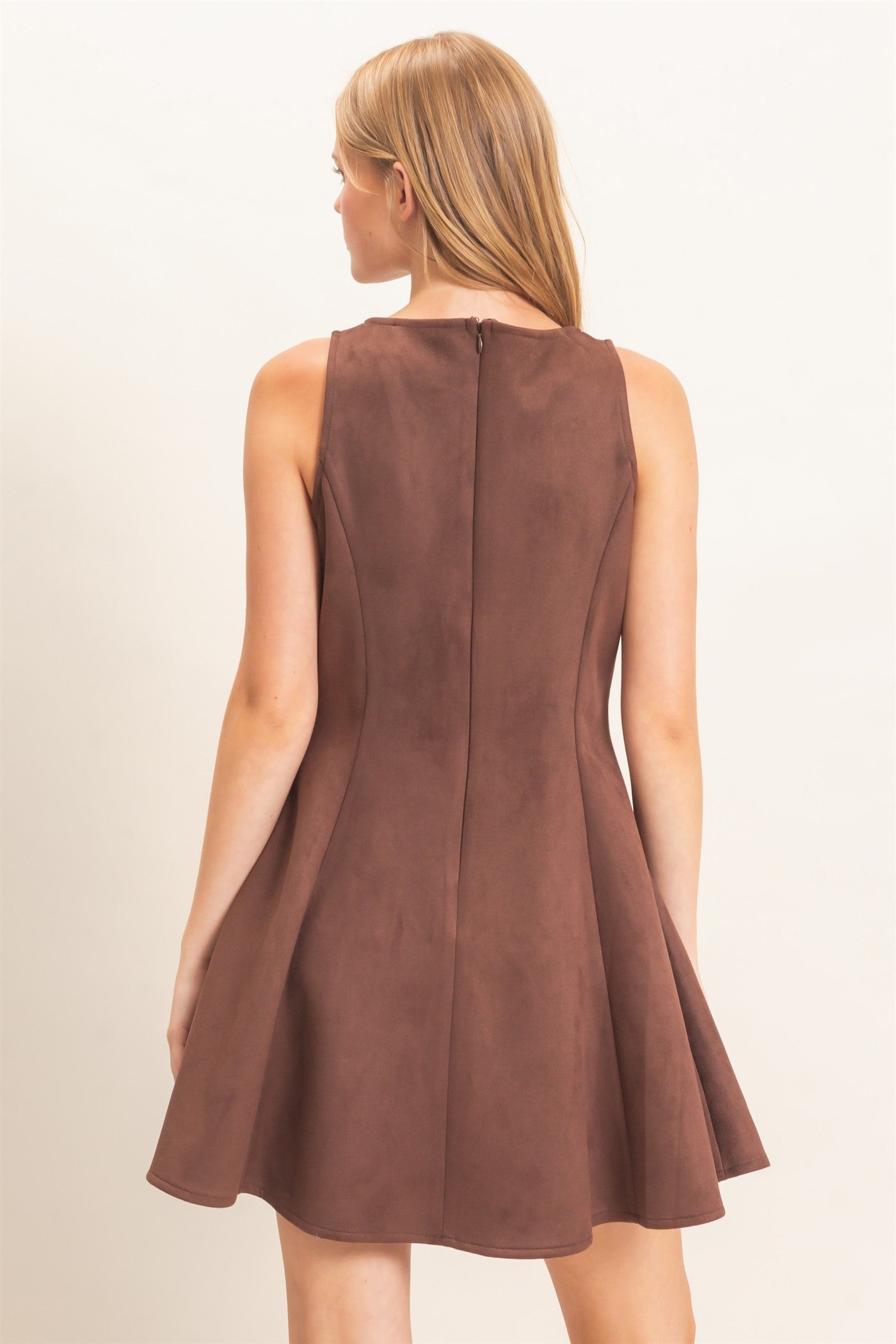 A sophisticated sleeveless suede mini dress with a classic round neckline and flattering flared silhouette that effortlessly transitions from day to night.
