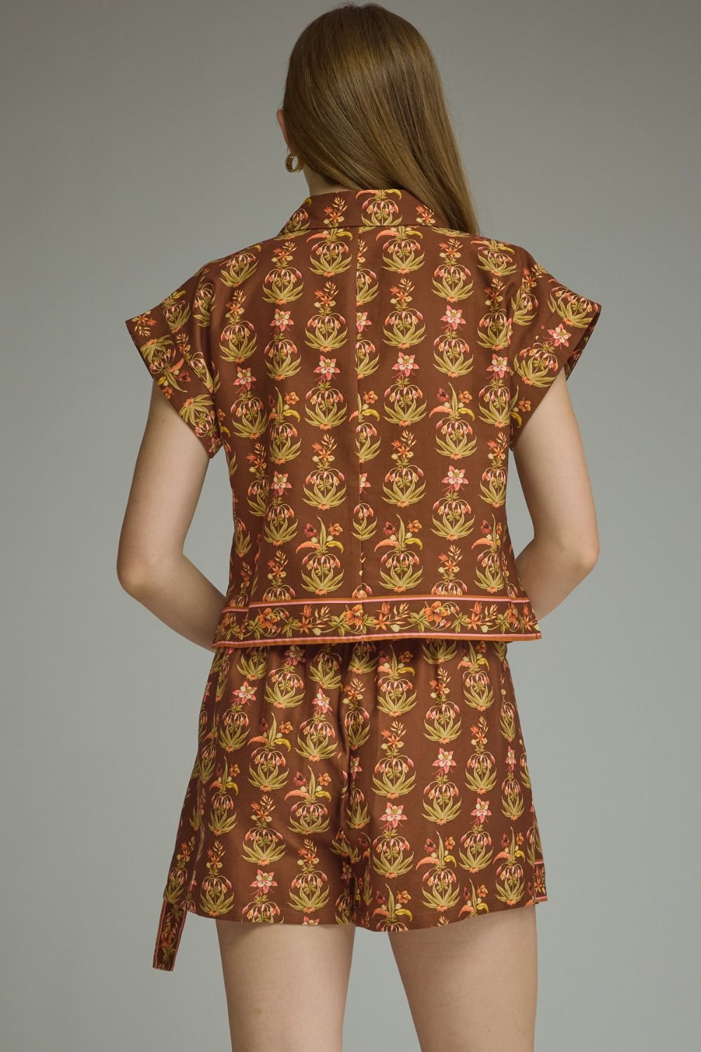 A feminine floral two-piece set featuring a flattering a contrast-trimmed V-neck top and coordinating wrap-front mini skort for an effortlessly polished boutique look.

