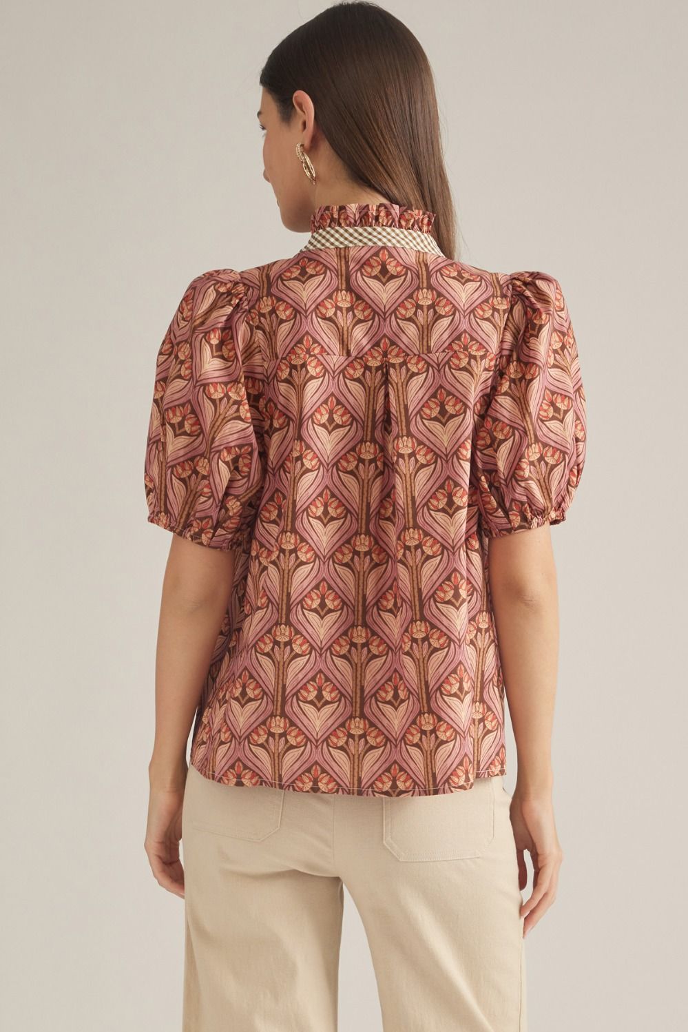 A feminine short sleeve top featuring a charming ruffled neckline, contrast trim, and button-front closure in a lightweight woven fabric.