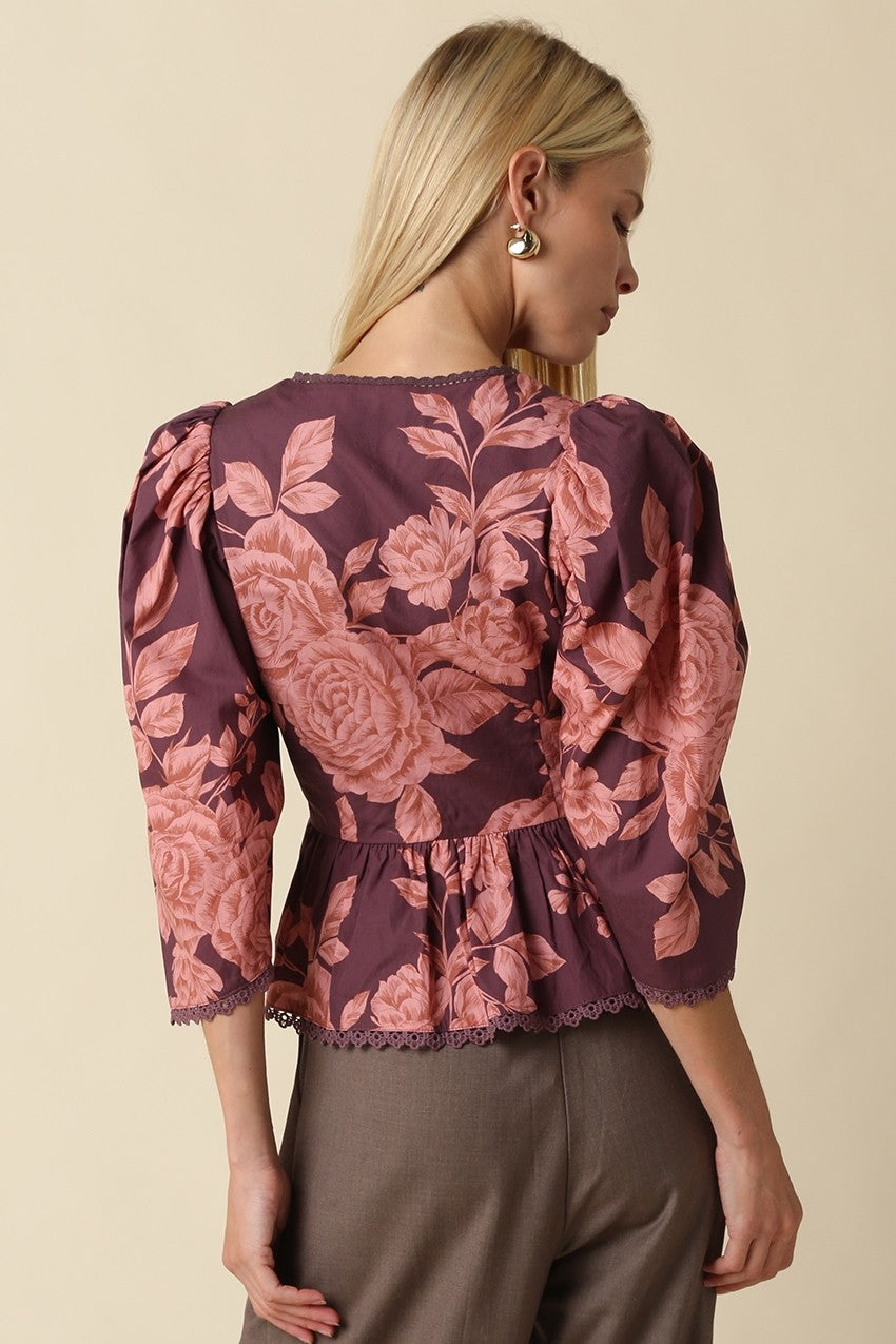 A vibrant floral cotton top featuring puff sleeves, a flattering peplum silhouette, and a lace trimmed hem for effortlessly feminine style.