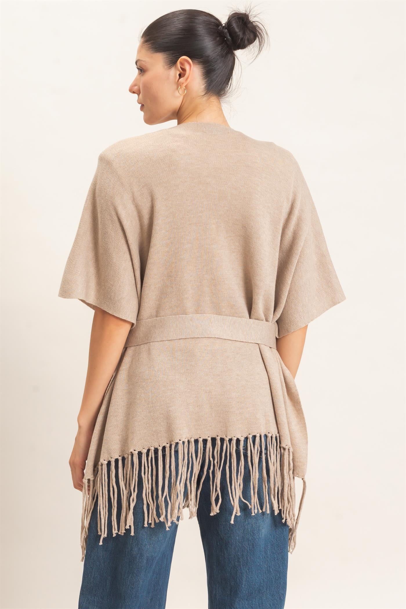 A chic open-front kimono sweater with wide sleeves, a self-tie waist, and statement fringe trim that adds effortless movement to any outfit.
