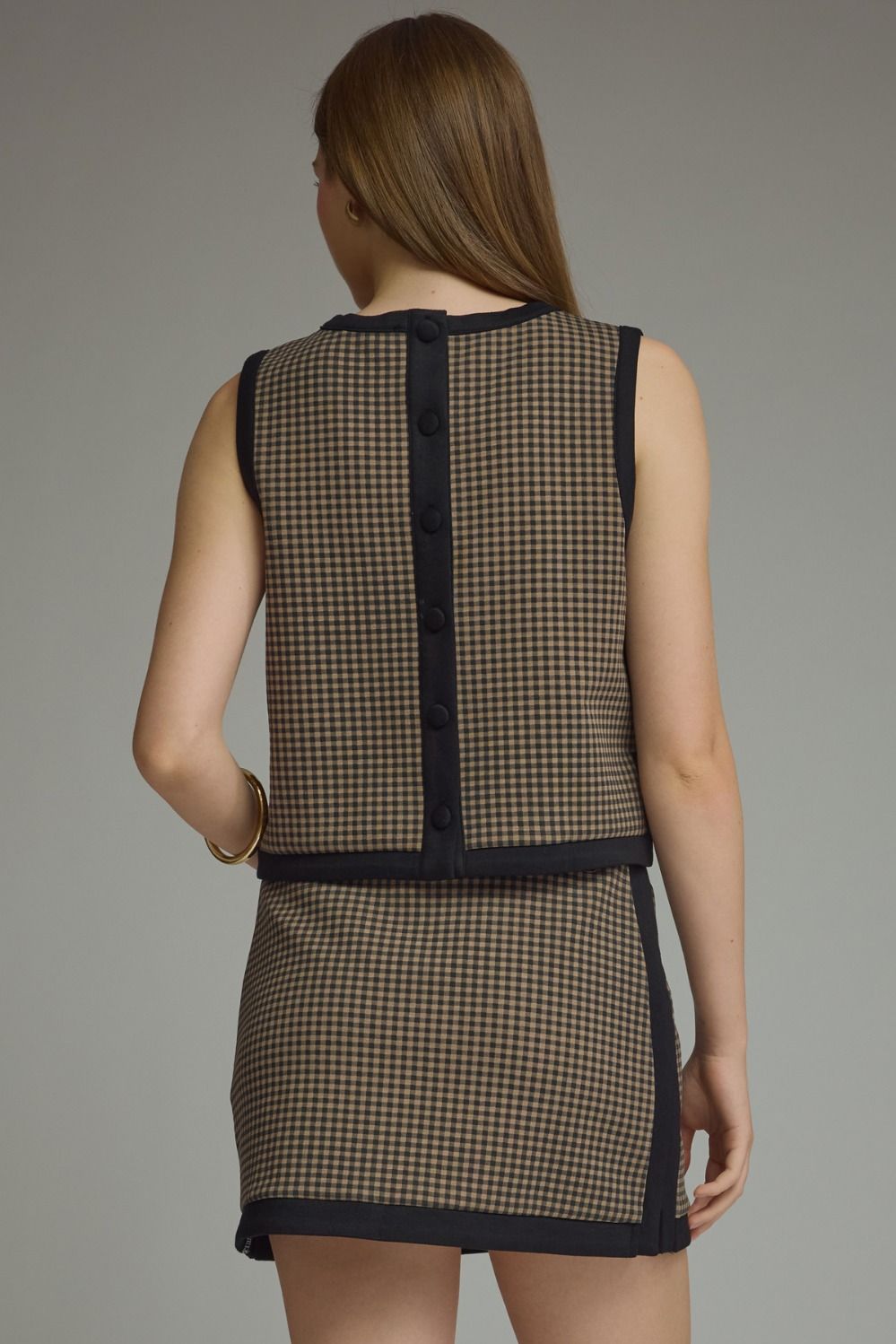 A charming gingham knit top featuring contrast binding, a layered hem, and a lightweight sleeveless silhouette perfect for effortless everyday style.