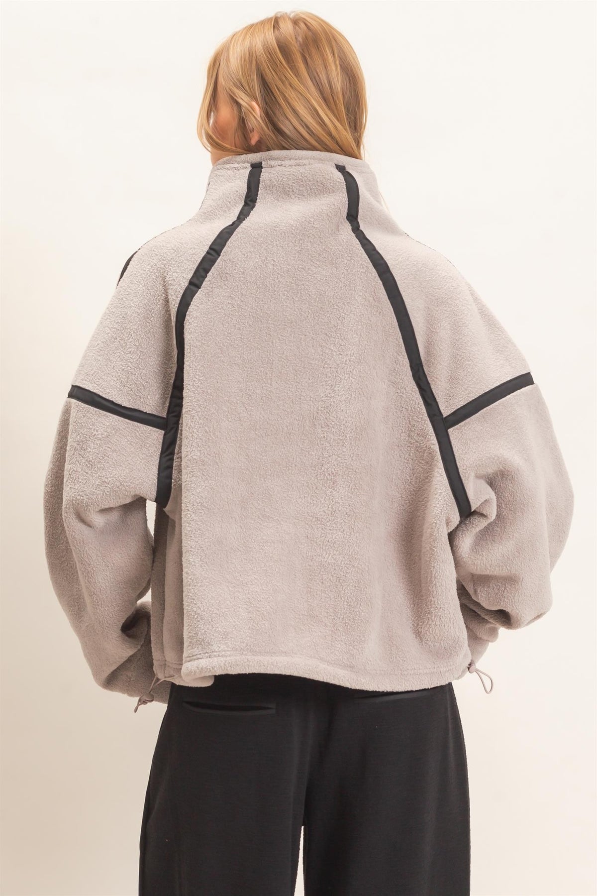 A cozy fleece half zip pullover featuring a high funnel neck, sporty contrast trim, oversized curved pockets, and an adjustable drawstring hem.