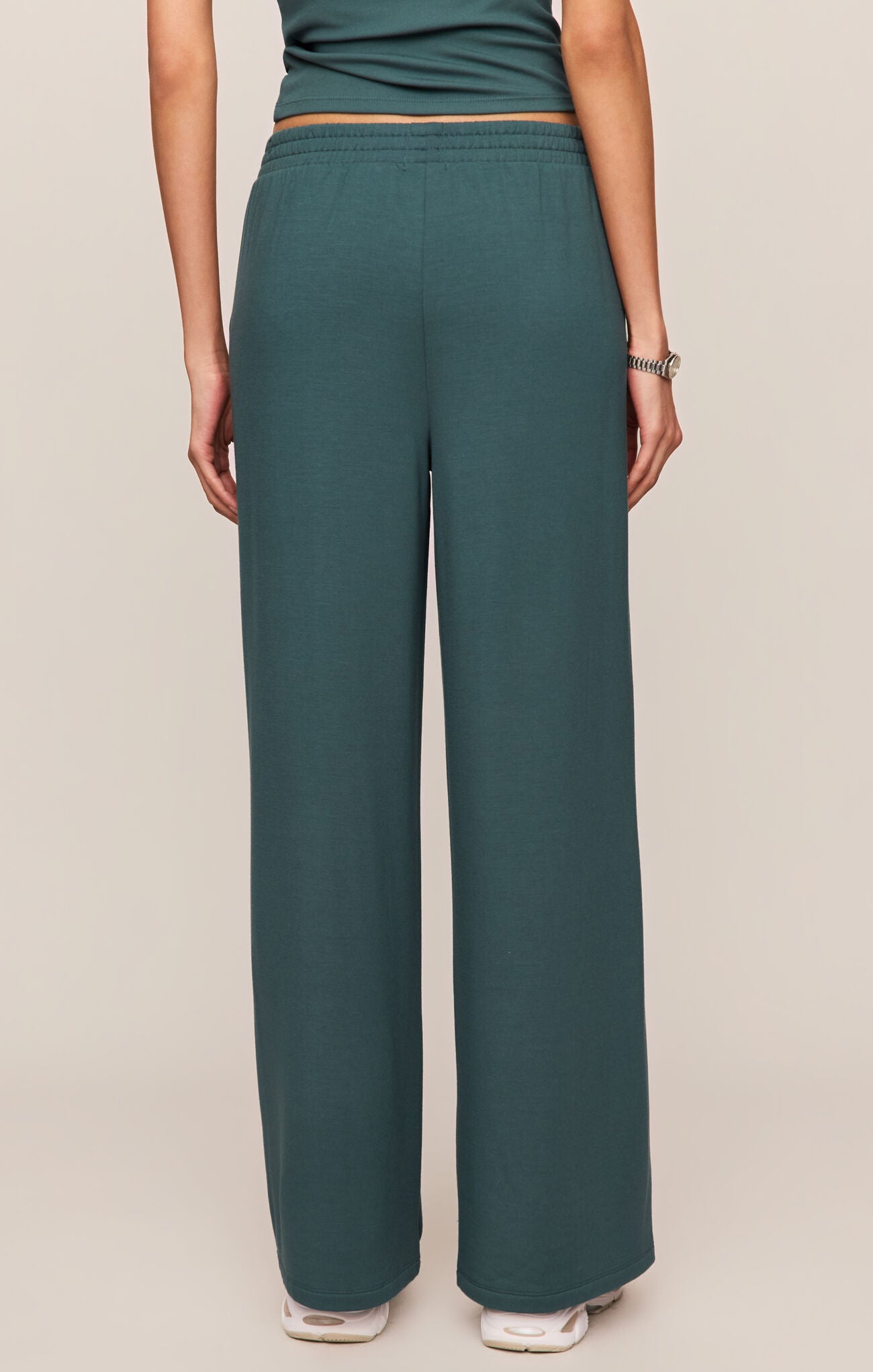 Teal pants worn by a person on a beige background