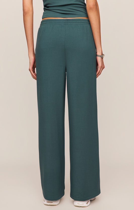 Teal pants worn by a person on a beige background