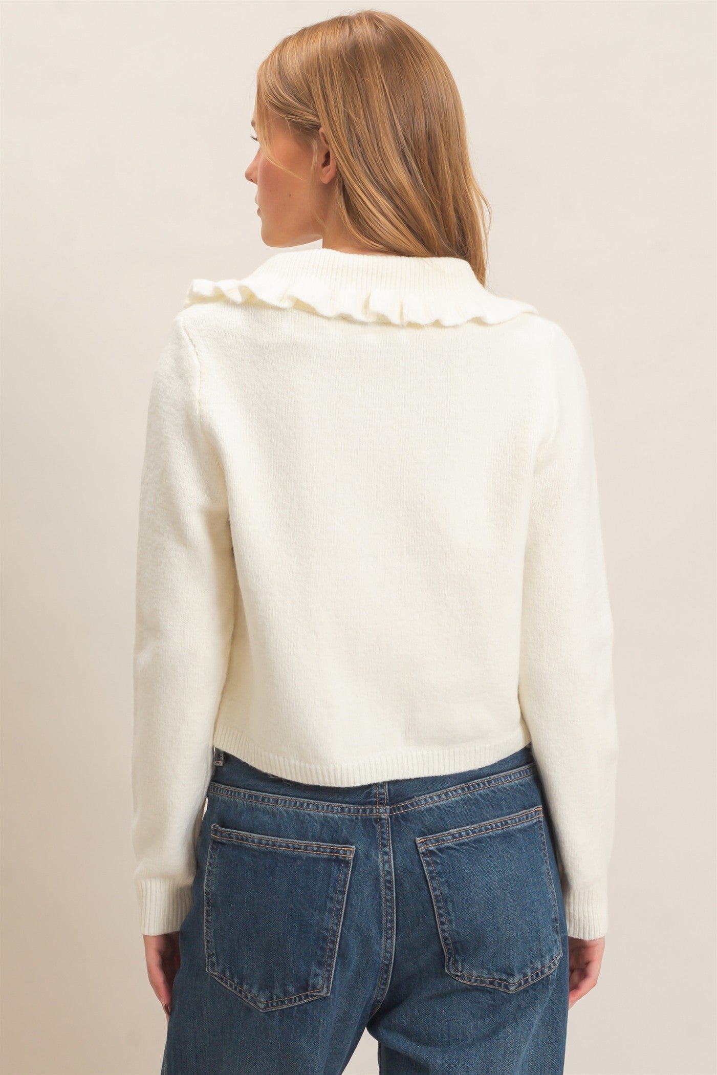 A polished knit cardigan featuring a feminine ruffled collar, classic button-front design, and ribbed cuffs for timeless everyday elegance.
