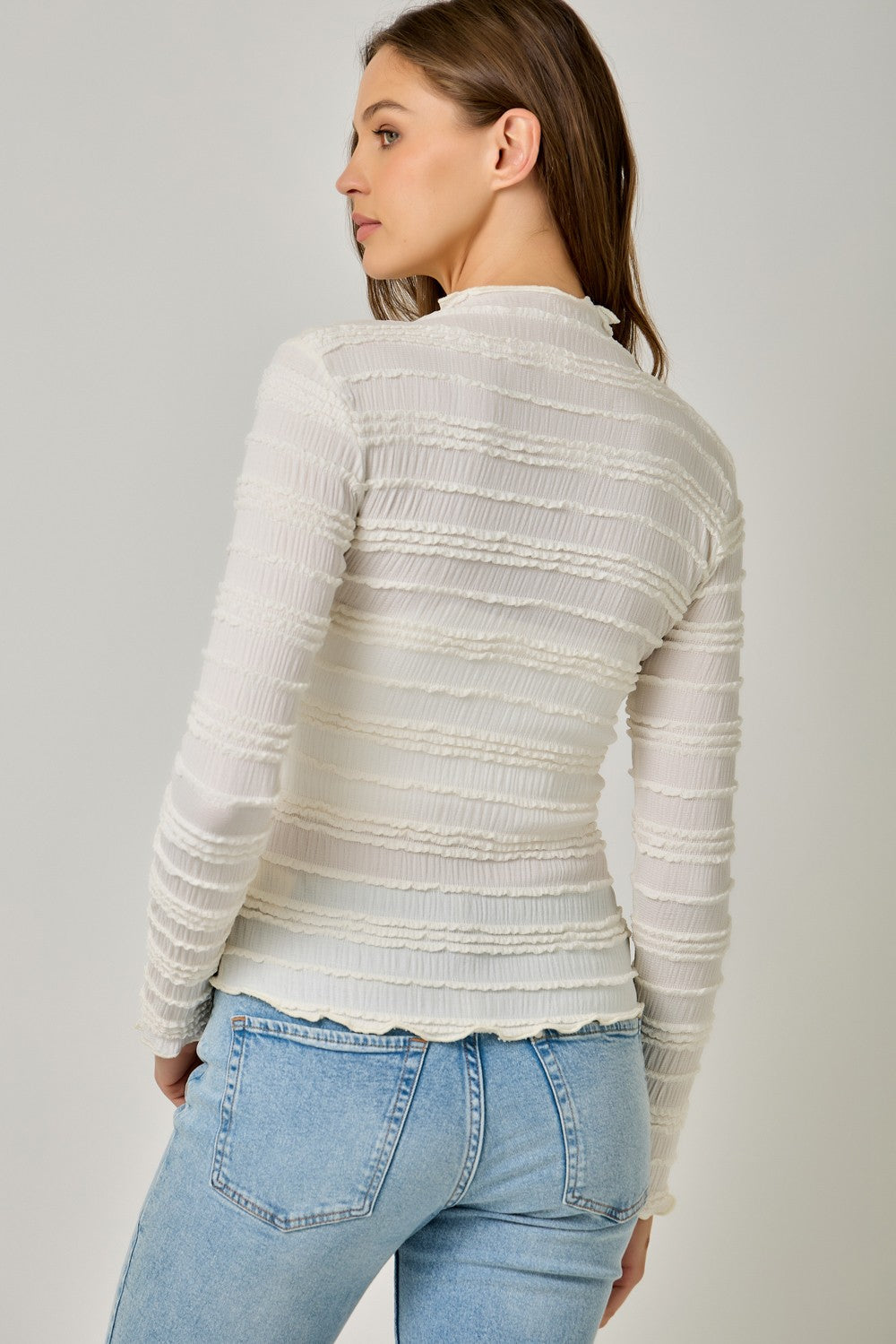 A feminine fitted knit top featuring a sleek mock neckline, long sleeves, and playful ruffled lettuce-edge stripes for a flattering statement look.
