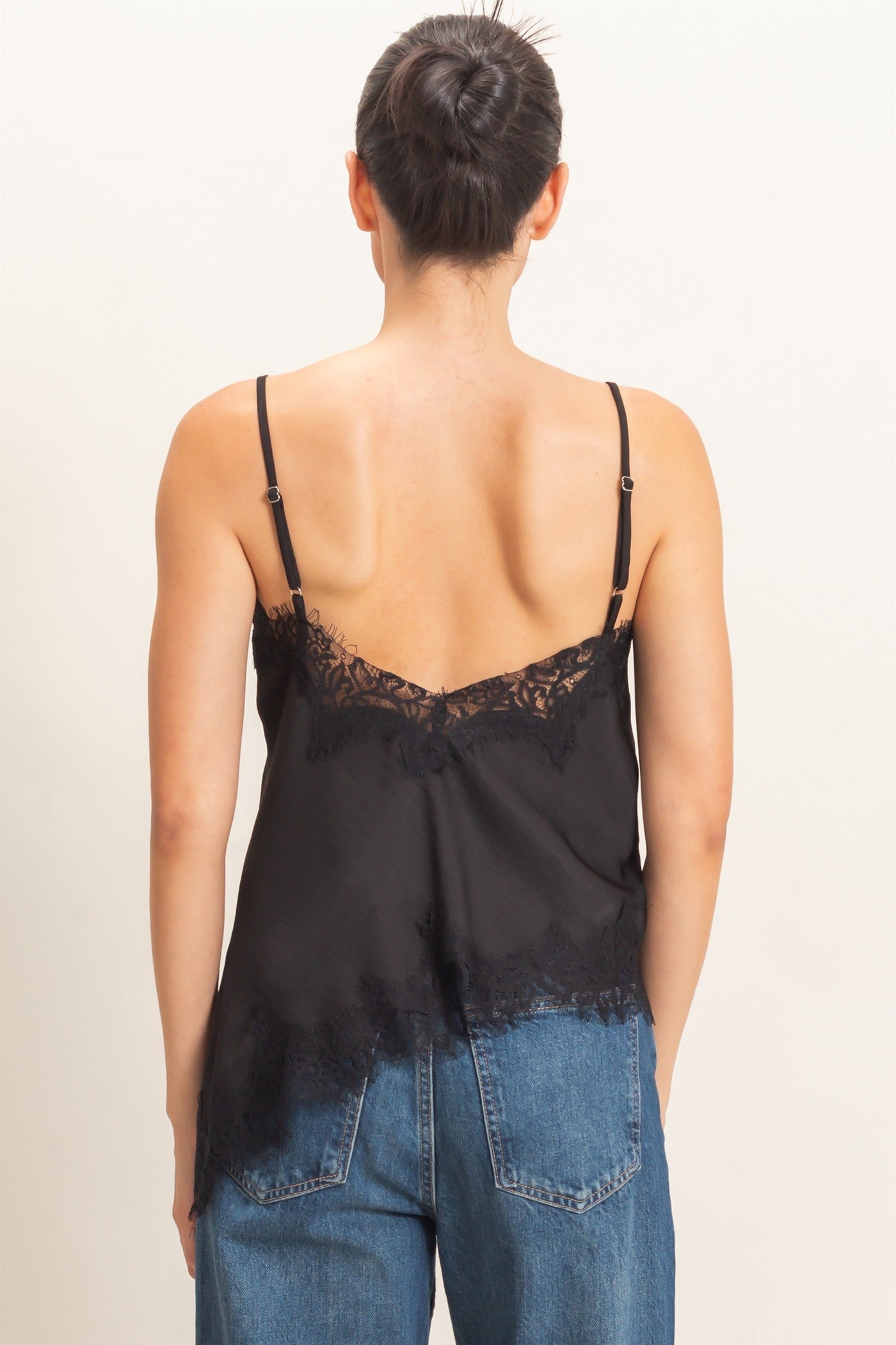 A delicate asymmetrical lace camisole with adjustable straps and feminine lace trim, designed to elevate your favorite layered looks.