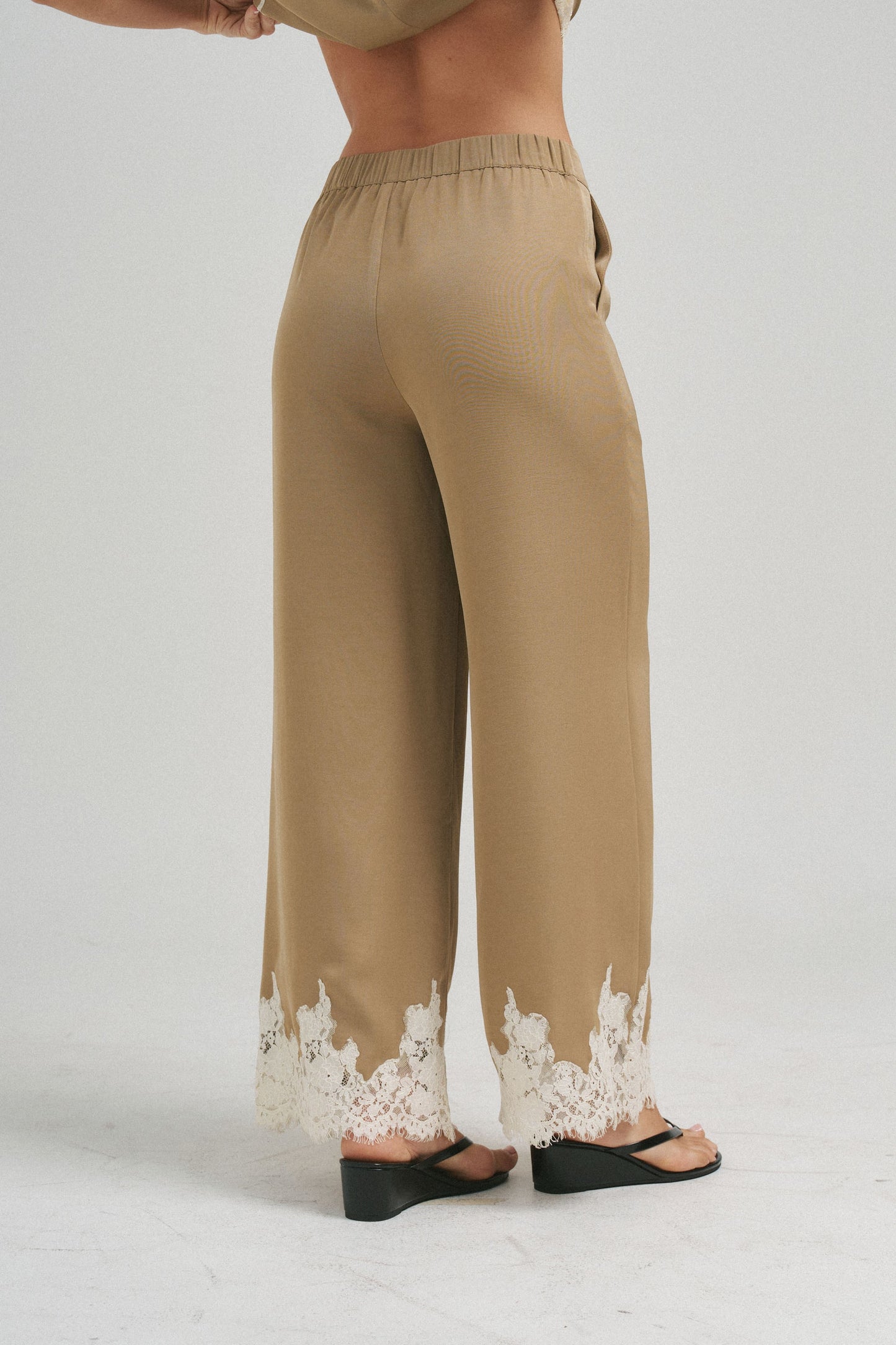 An effortlessly elegant two-piece set featuring delicate lace trim, a gathered neckline, and flowing wide-leg pants for timeless sophistication.
