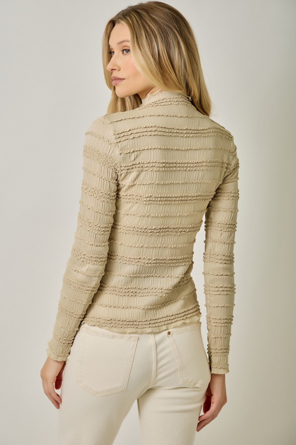 A feminine fitted knit top featuring a sleek mock neckline, long sleeves, and playful ruffled lettuce-edge stripes for a flattering statement look.
