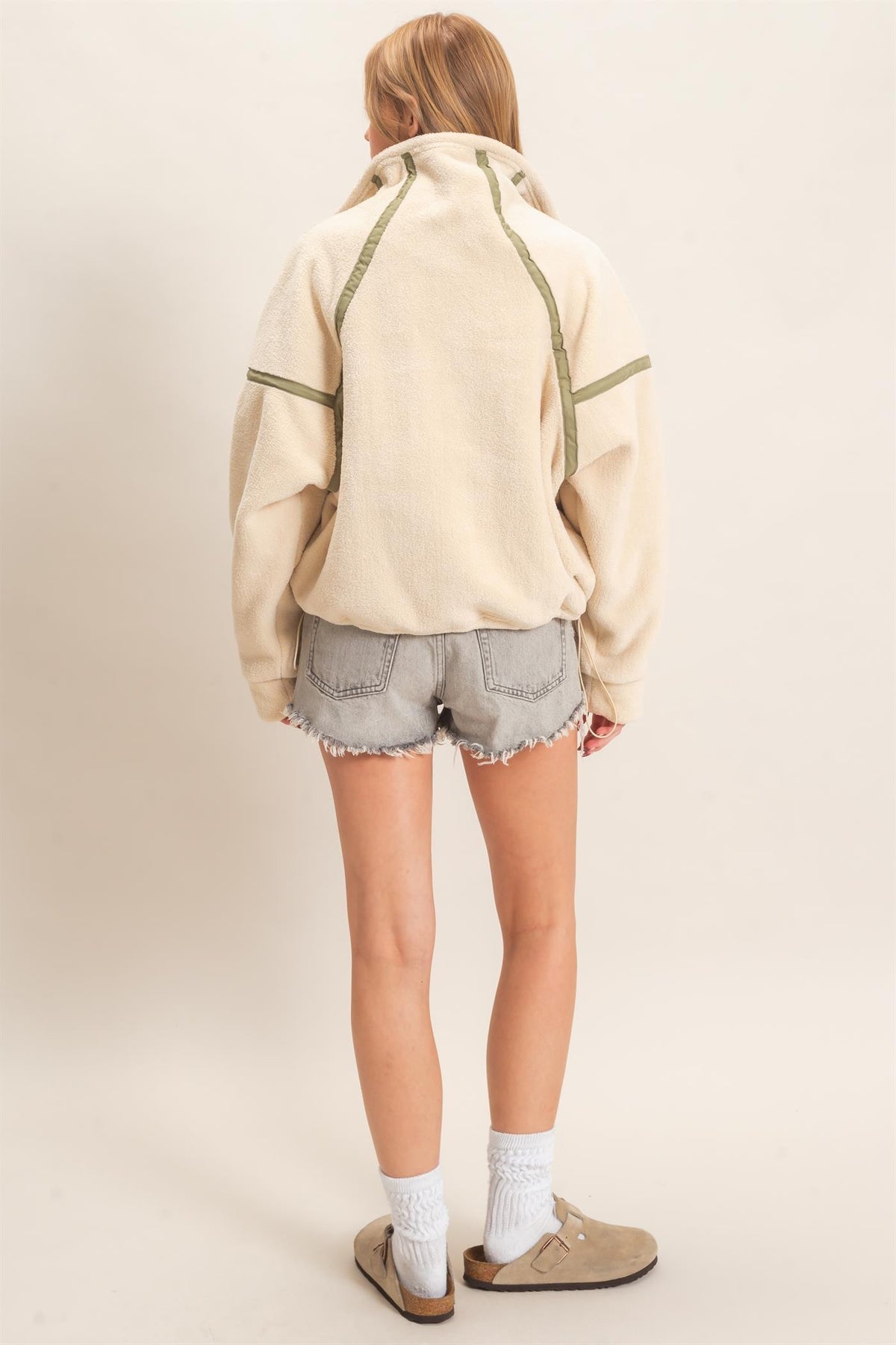 A cozy fleece half zip pullover featuring a high funnel neck, sporty contrast trim, oversized curved pockets, and an adjustable drawstring hem.