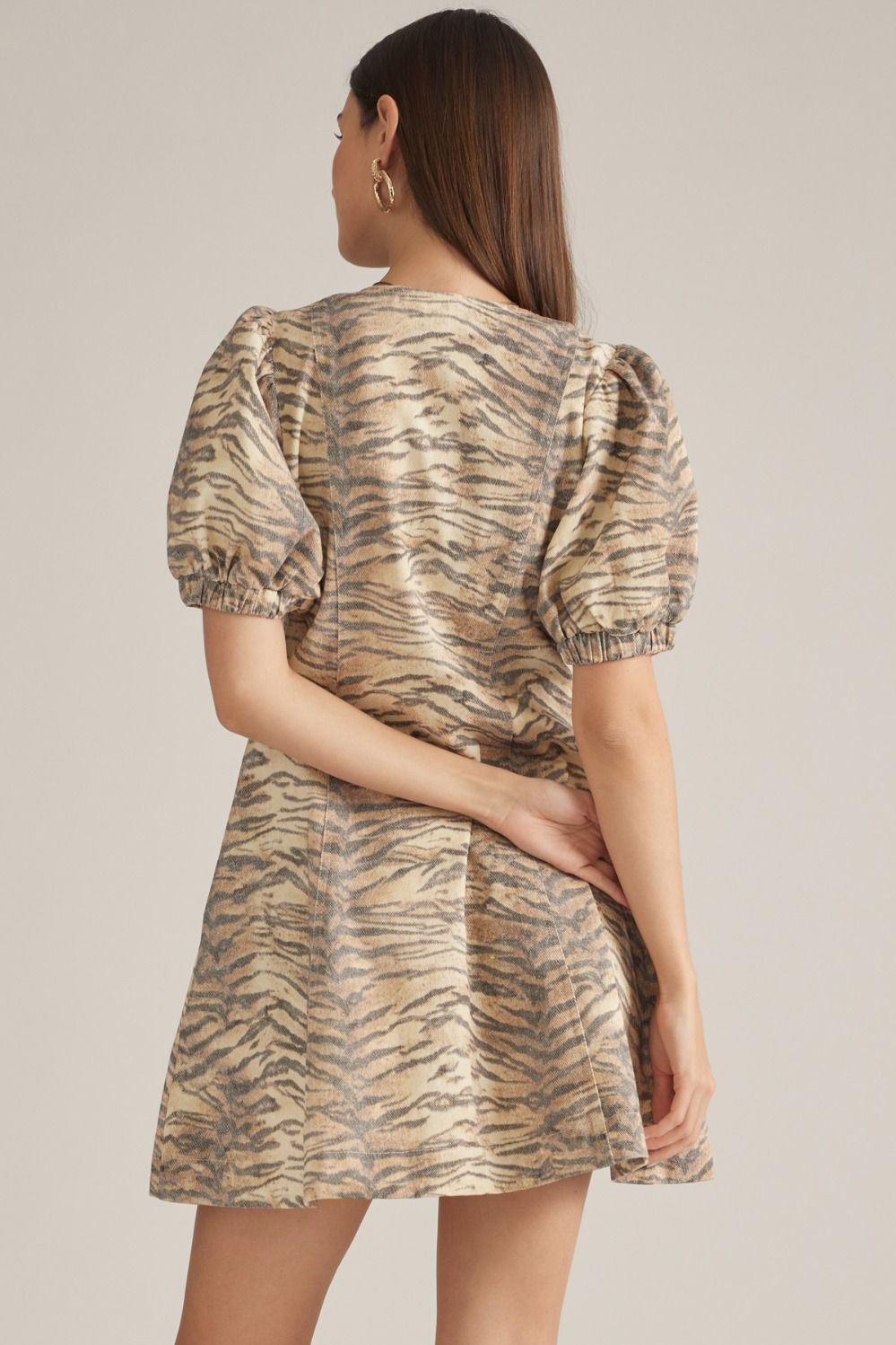 A playful cotton mini dress featuring a flattering V-neckline, short puff sleeves, and an easy front zipper closure in a chic animal print.

