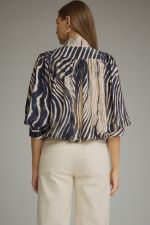 A statement-making zebra print top featuring elegant ¾ balloon sleeves, a stand collar, gathered details, and a polished banded hem.

