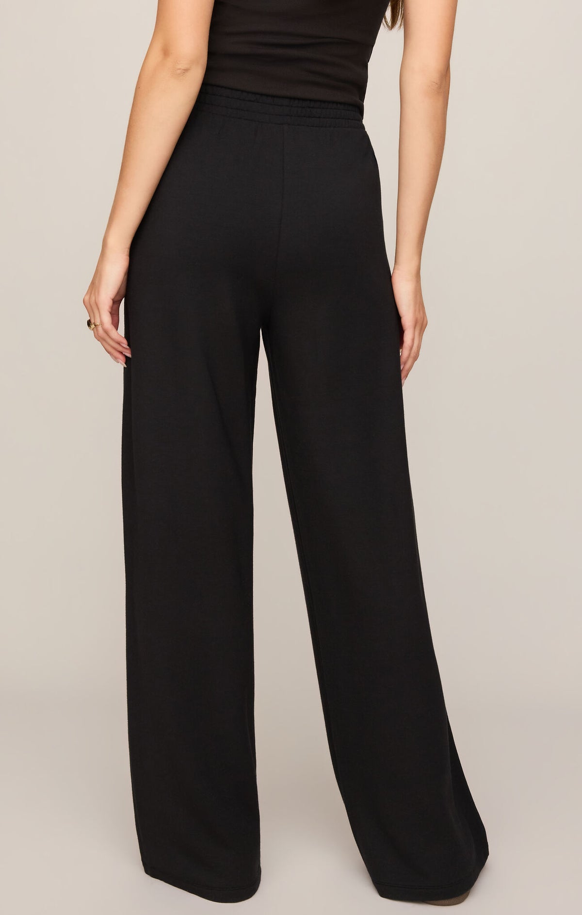 Black wide-leg pants worn by a person on a beige background