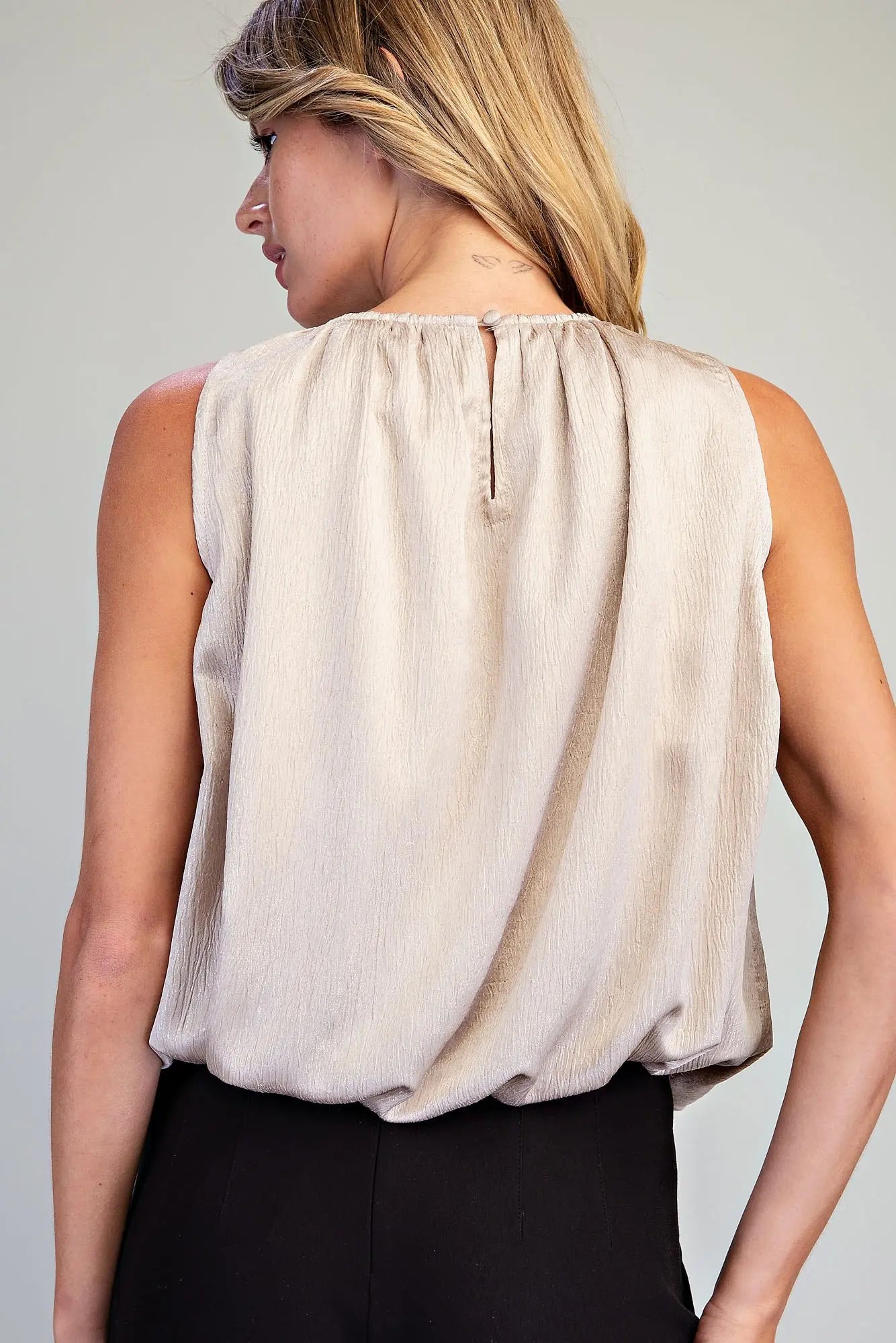 Genevieve Shimmer Bubble Top featuring a metallic shimmer texture, gathered high neckline, sleeveless design, bubble hem silhouette, and back keyhole closure