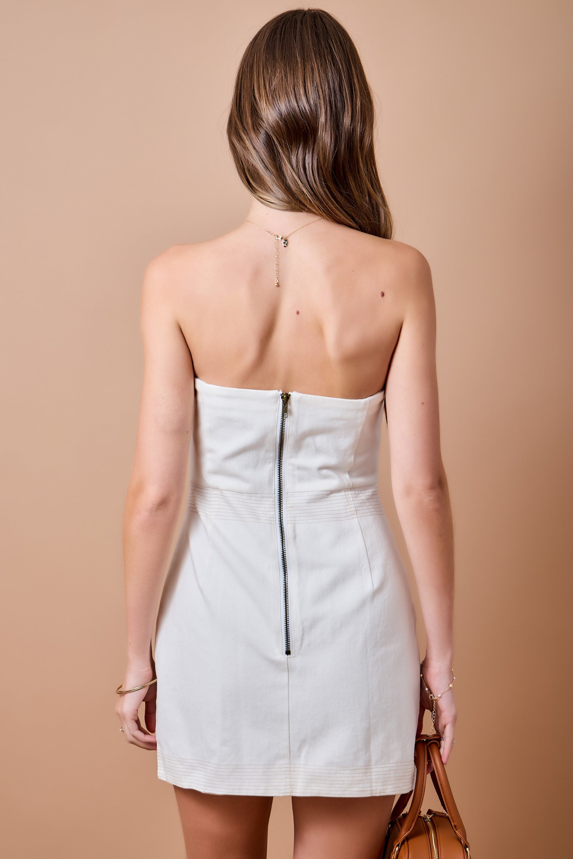 The Colette Strapless Cutout Dress makes a sleek statement with a fitted silhouette, waist cutout, and contrasting topstitch detail.
