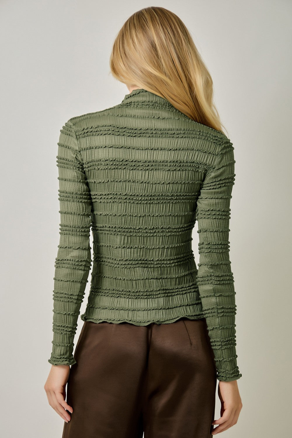 A feminine fitted knit top featuring a sleek mock neckline, long sleeves, and playful ruffled lettuce-edge stripes for a flattering statement look.
