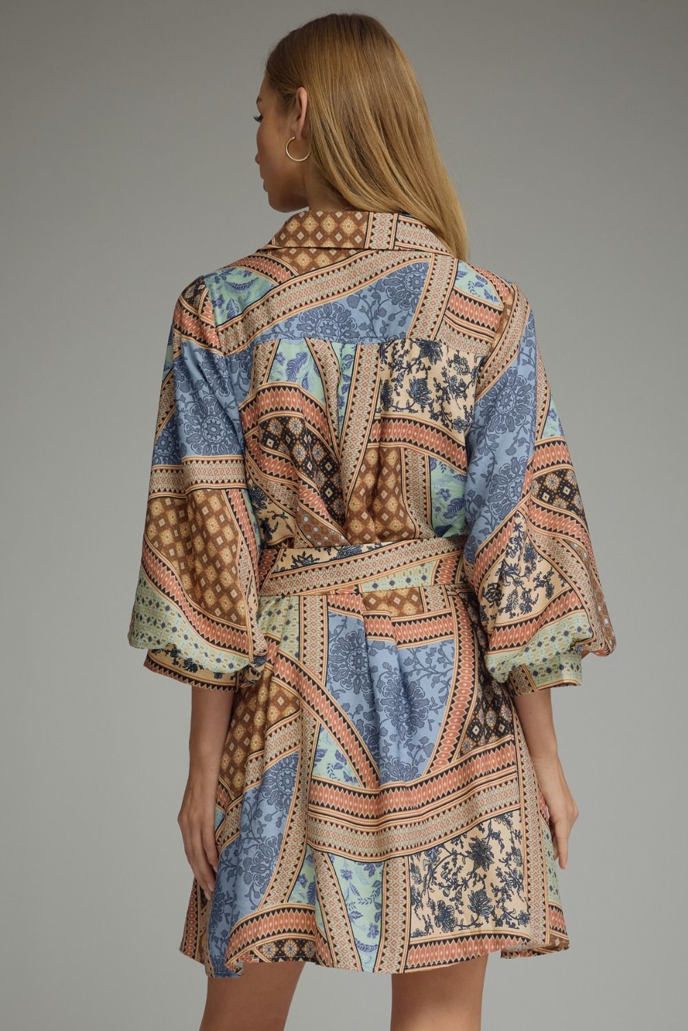 A charming patchwork print mini dress featuring ¾ sleeves, a button-front closure, self-tie waist, and convenient side pockets for effortless everyday style.
