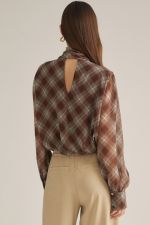 A sophisticated plaid blouse featuring a high neckline, elegant draped crossover front, self-tie back detail, and button cuffs.
