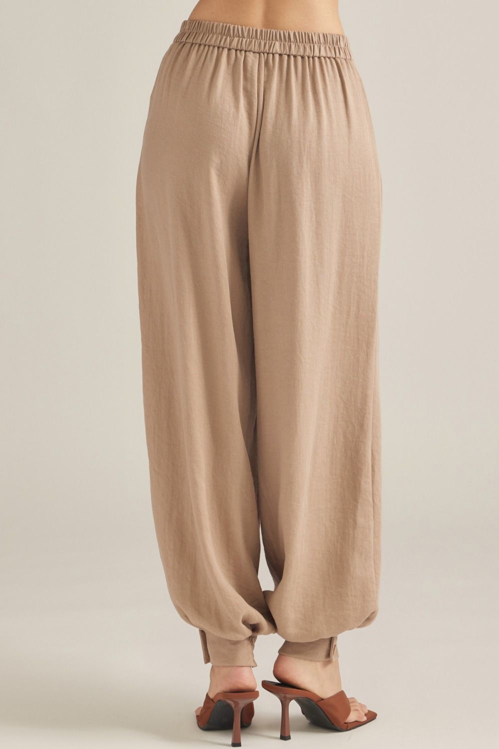 Polished woven pants featuring elegant front pleats, a comfortable elastic-back waist, and buttoned cuffs for an effortlessly tailored look.
