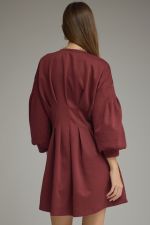 A timeless solid mini dress featuring a flattering pleated waist, classic round neckline, long sleeves, and convenient side pockets.

