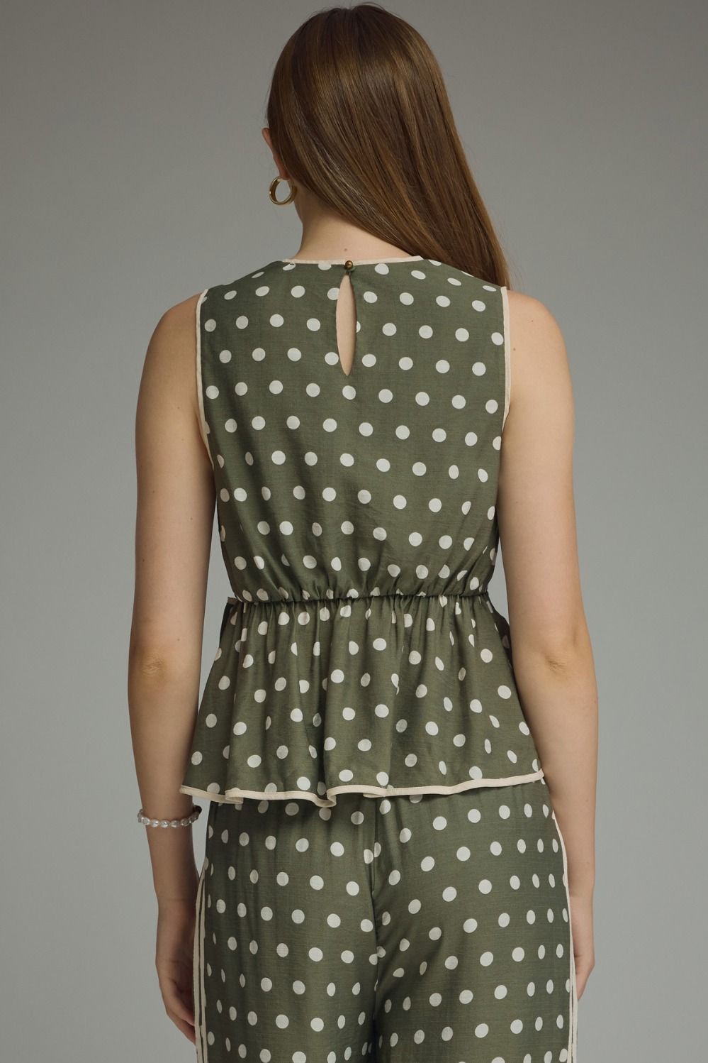 A timeless polka dot sleeveless top featuring a flattering tie waist and contrast trim for an effortlessly polished look.
