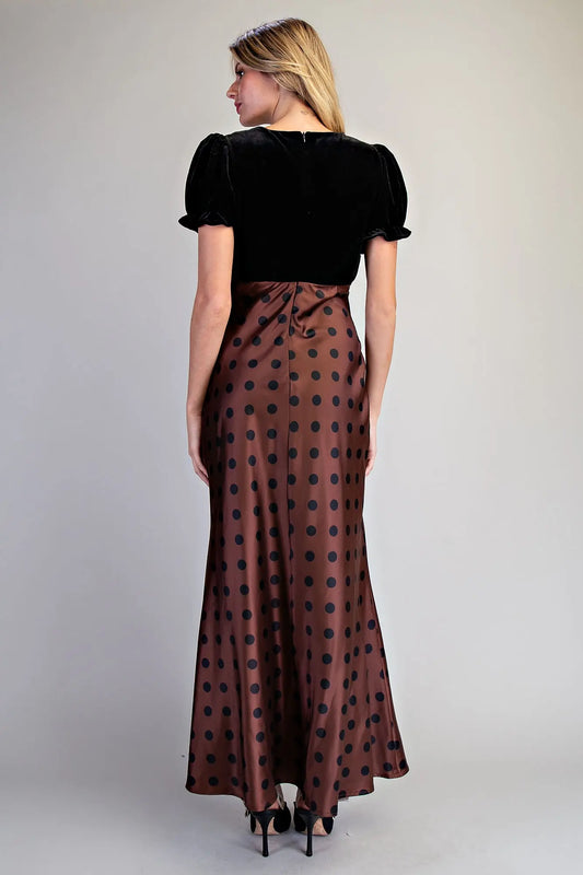 A romantic vintage-inspired maxi dress combining a velvet bodice, ruffled puff sleeves, bow neckline, and flowing satin polka dot skirt.