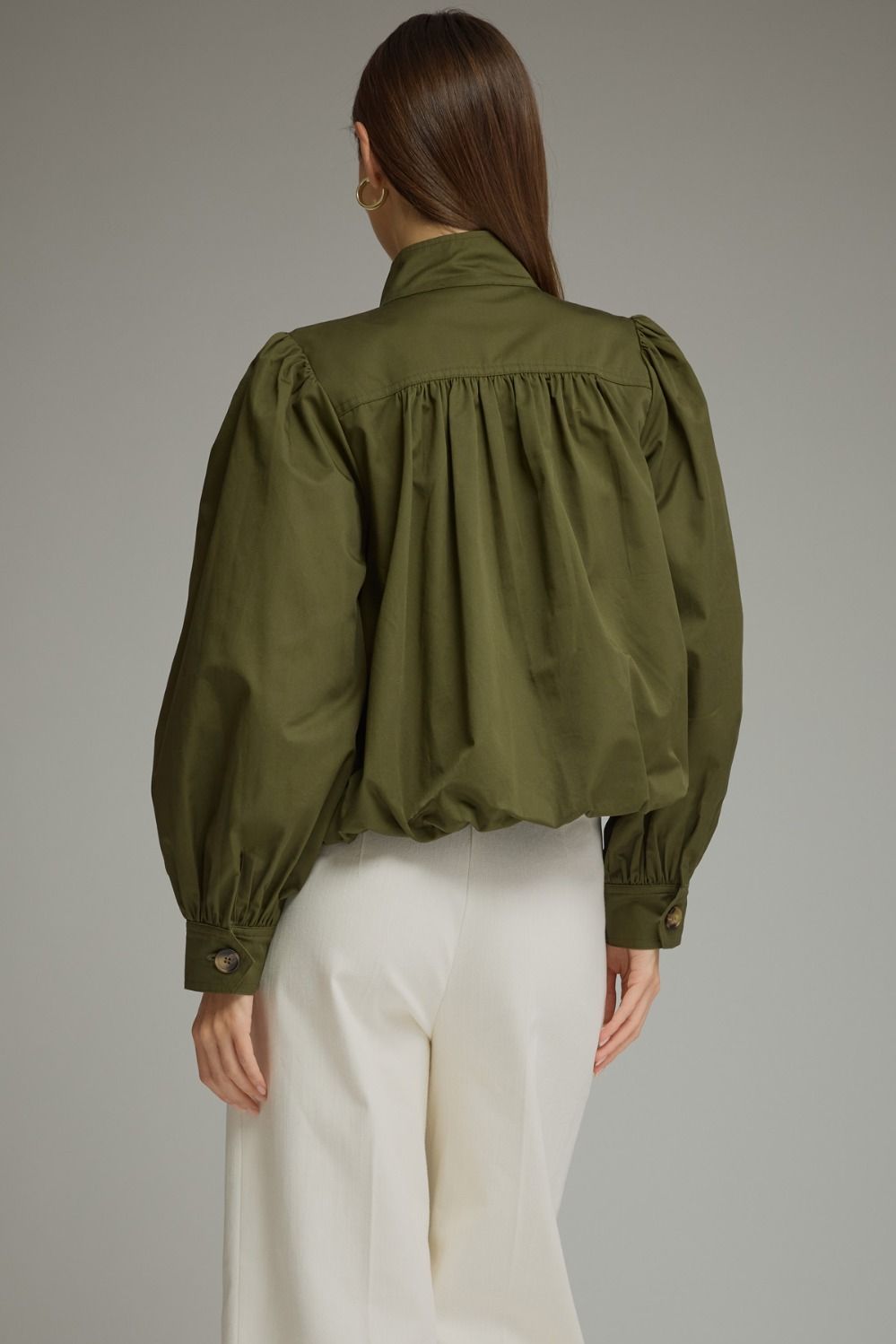 A polished everyday jacket featuring dramatic puff sleeves, a structured stand collar with a unique button closure, and a flattering elastic hem.

