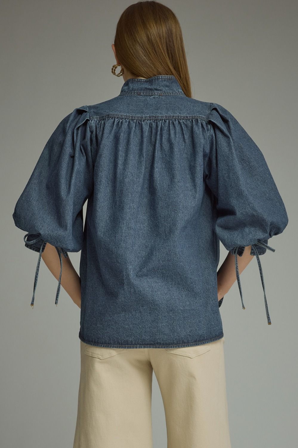 A feminine lightweight denim top featuring romantic ¾ puff sleeves, a classic button-front closure, and adjustable self-tie cuffs for a polished everyday look.
