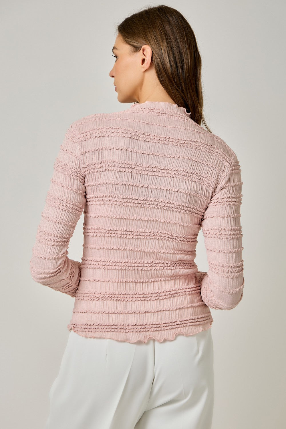 A feminine fitted knit top featuring a sleek mock neckline, long sleeves, and playful ruffled lettuce-edge stripes for a flattering statement look.

