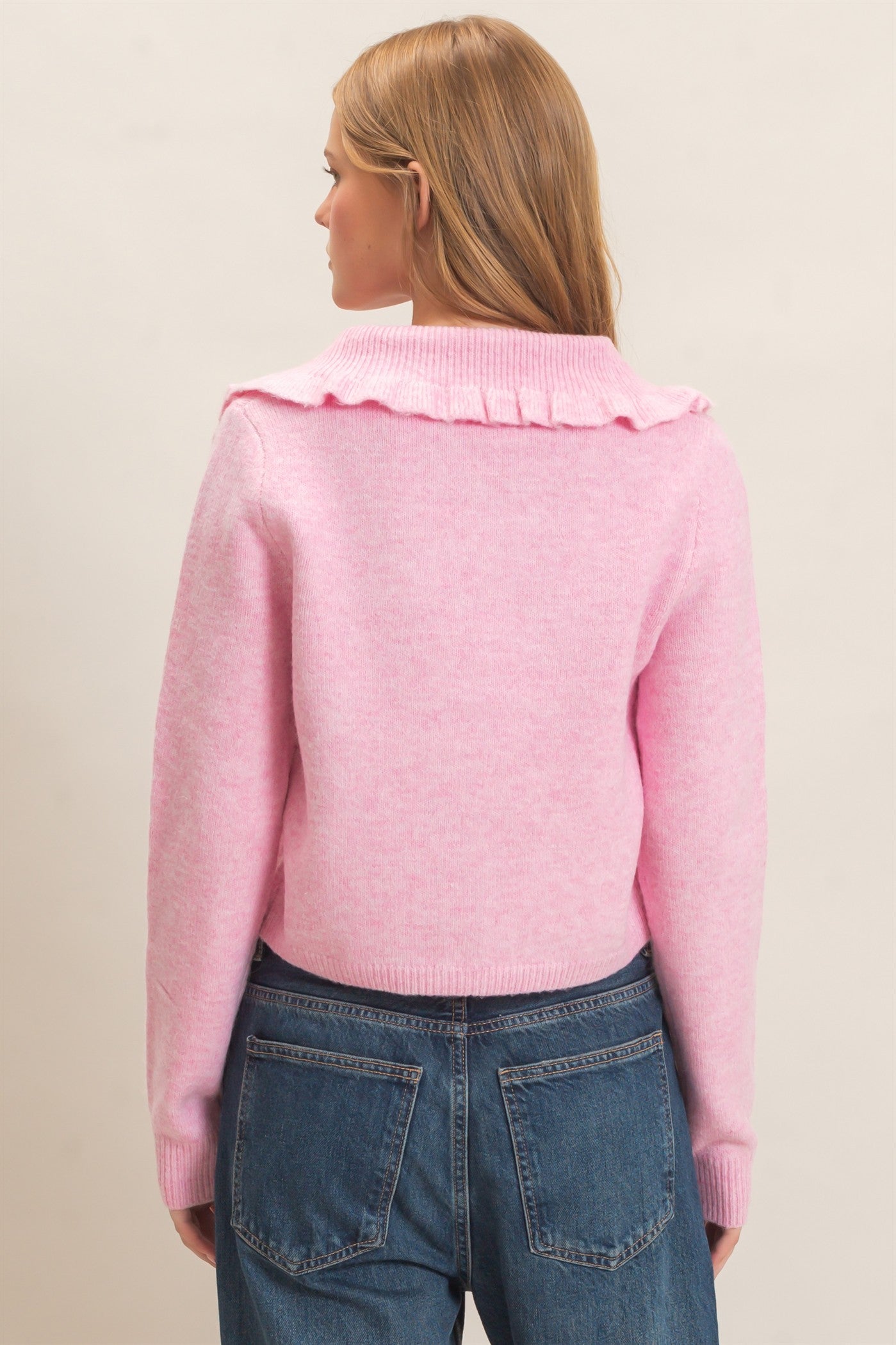 A polished knit cardigan featuring a feminine ruffled collar, classic button-front design, and ribbed cuffs for timeless everyday elegance.
