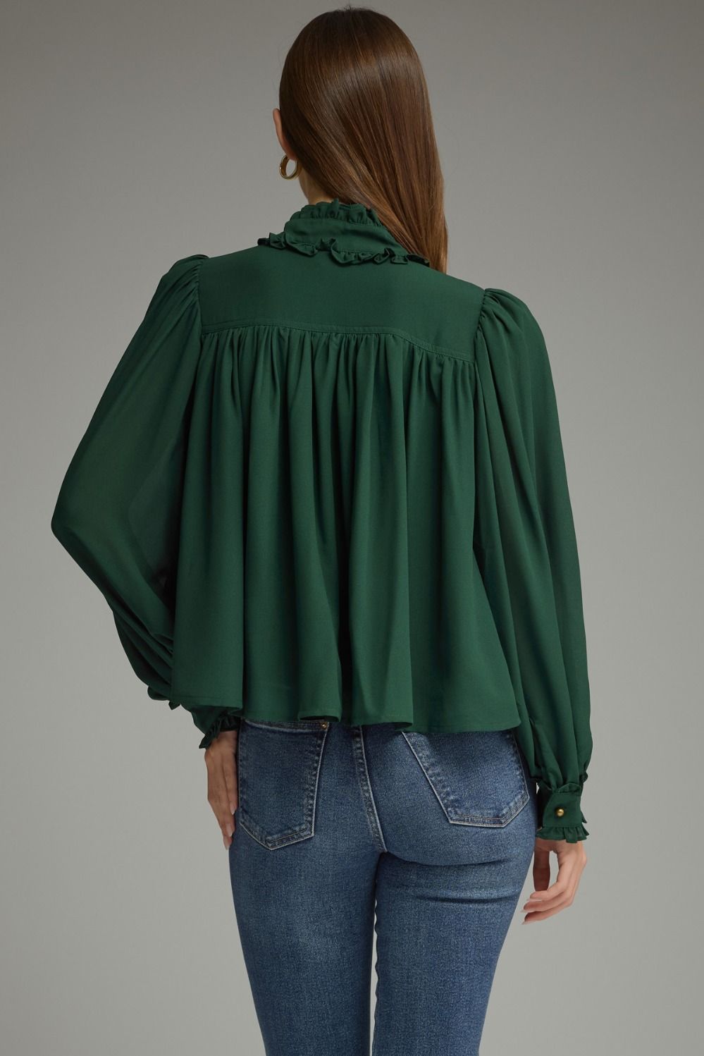 A romantic long sleeve blouse featuring a ruffled high neckline, gathered details, voluminous sleeves, and delicate ruffle-trimmed cuffs.

