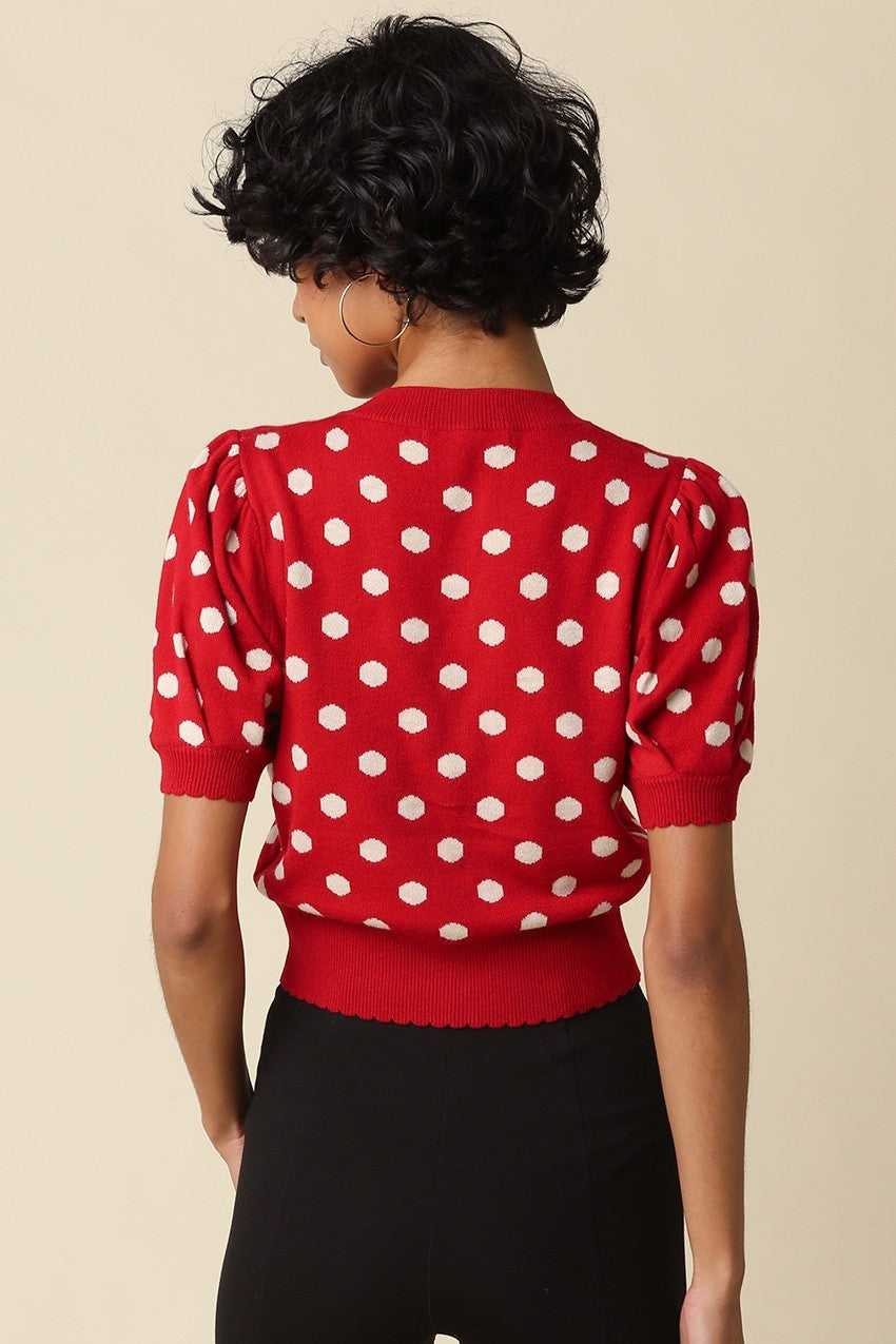 A feminine cropped polka dot cardigan featuring short puff sleeves, a scalloped hem, and a flattering fitted silhouette in a soft stretch wool blend.